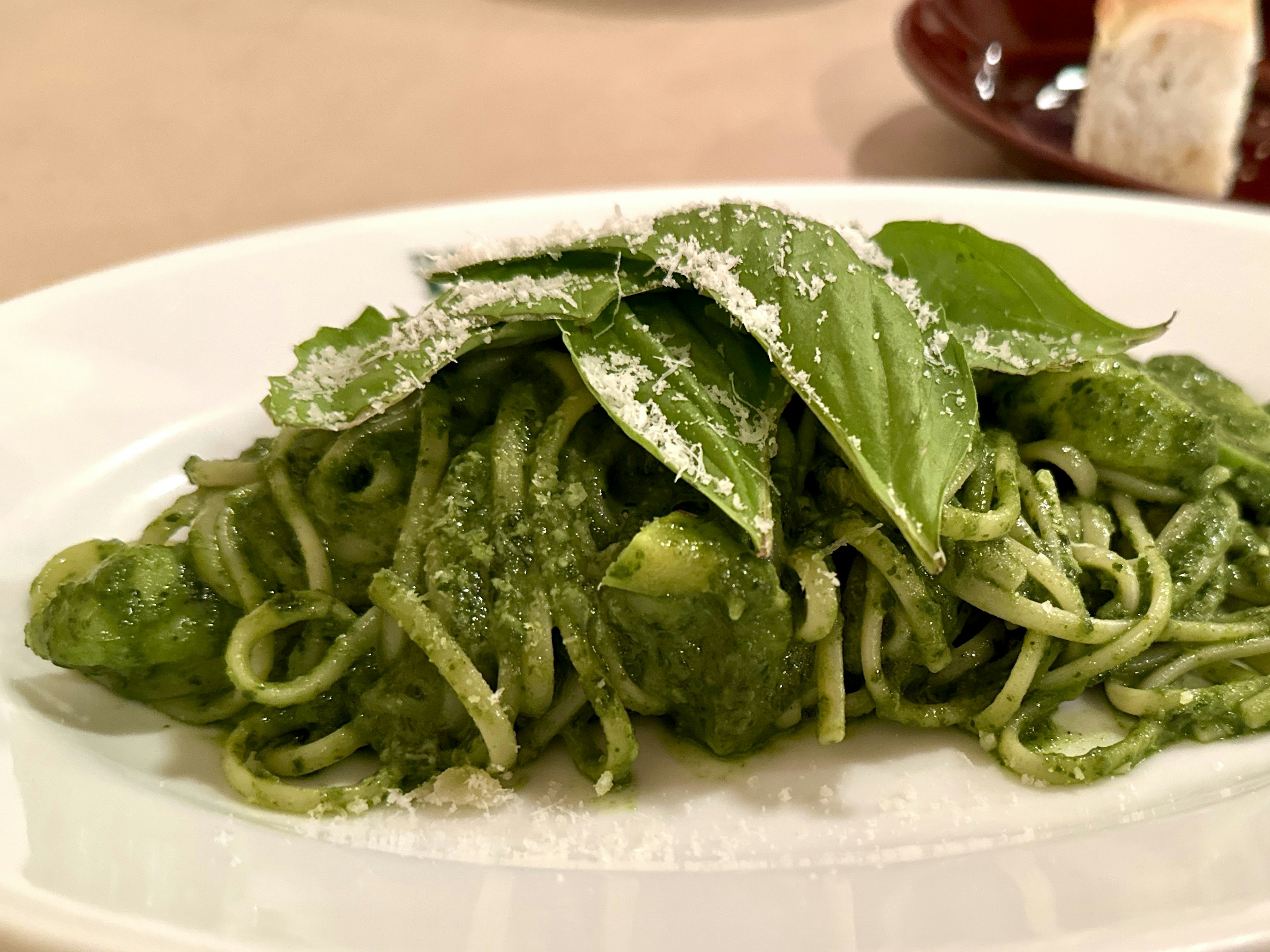 Plate of spaghetti topped with green basil leaves and parmesan cheese