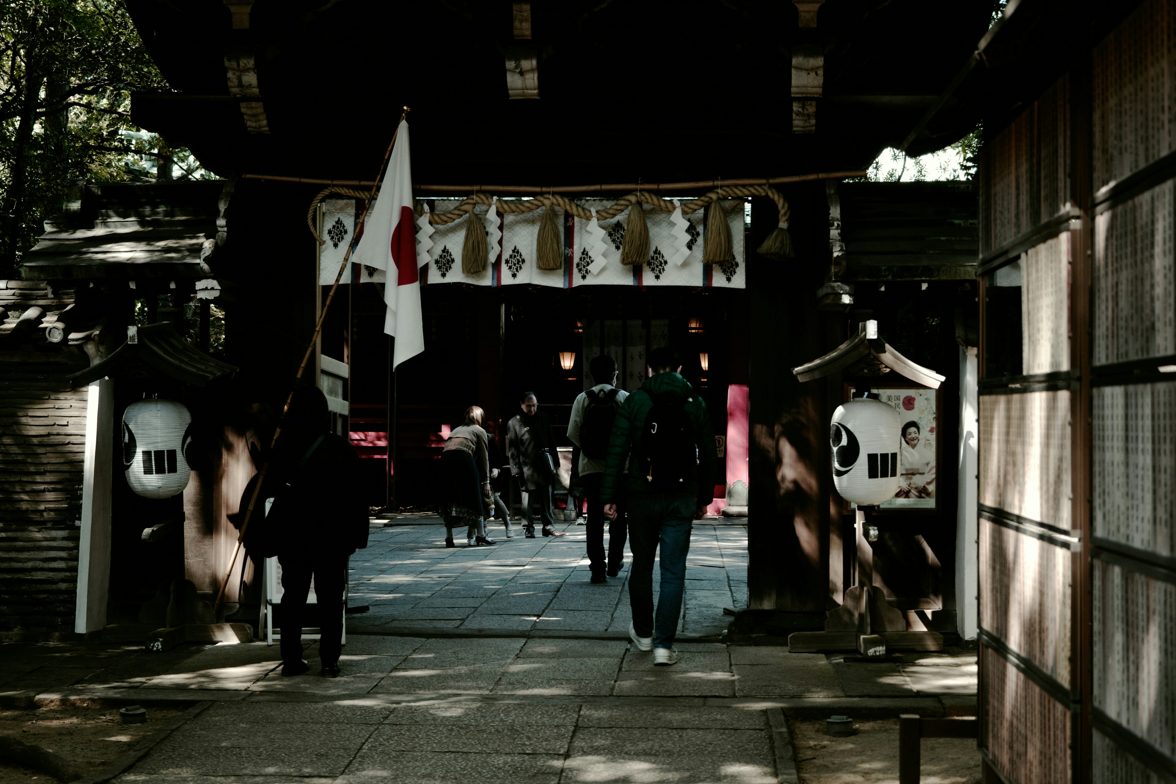 Entrance of a Japanese shrine with visitors and lanterns