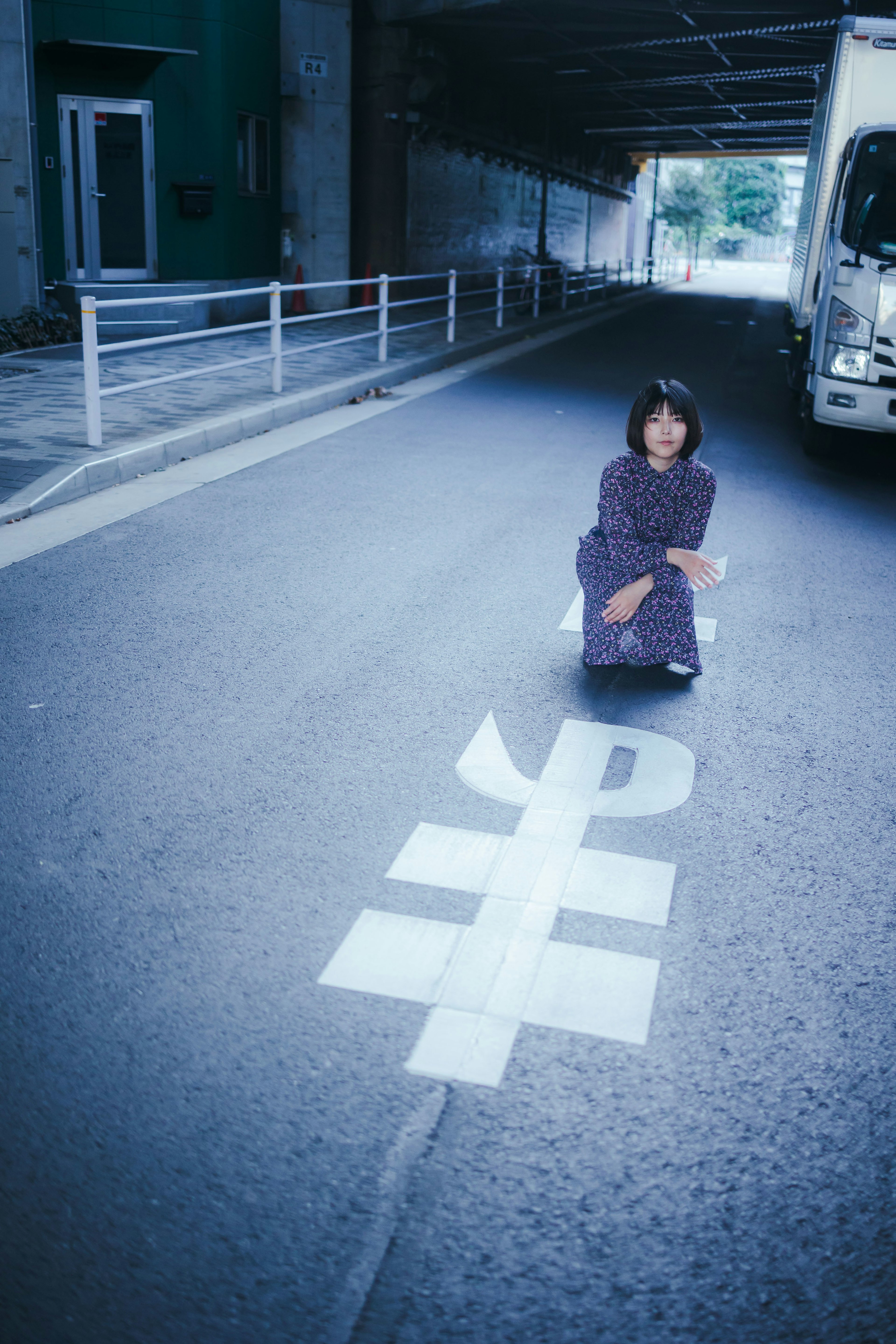 道路の上にしゃがむ女性が紫色の服を着ている