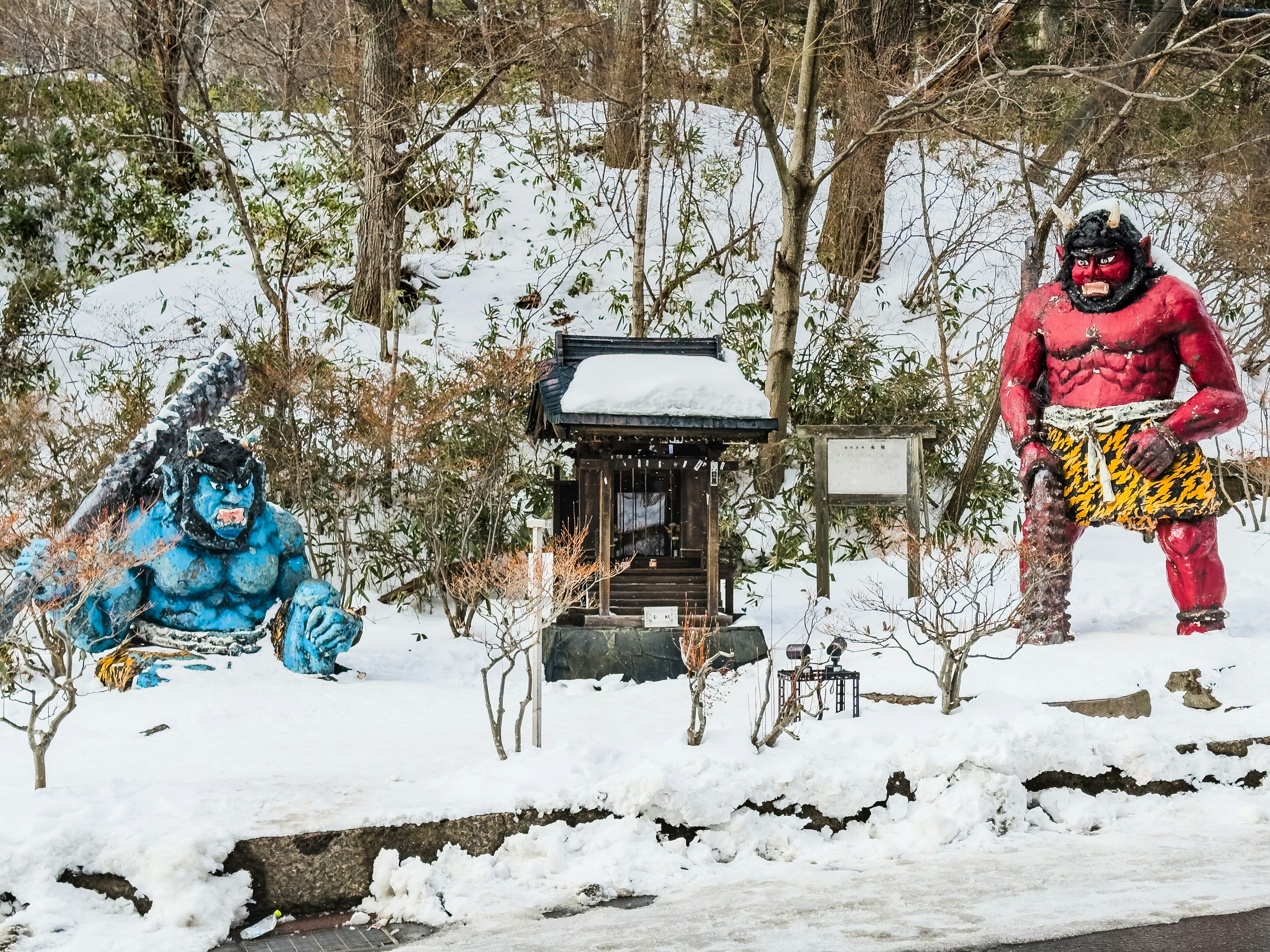 Statuen eines blauen Ogers und eines roten Ogers in einer schneebedeckten Landschaft