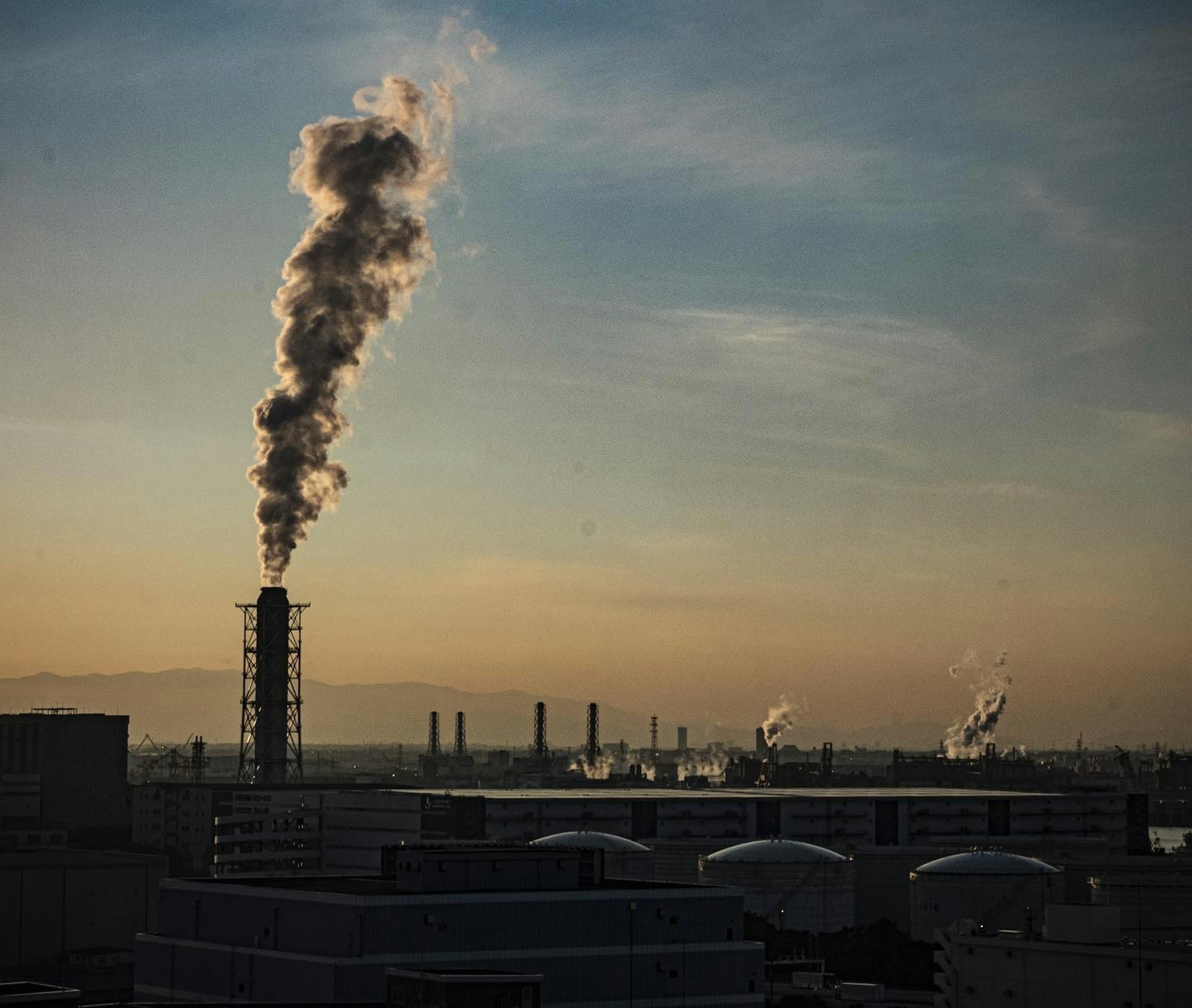 Smoke rising from a factory chimney during sunset