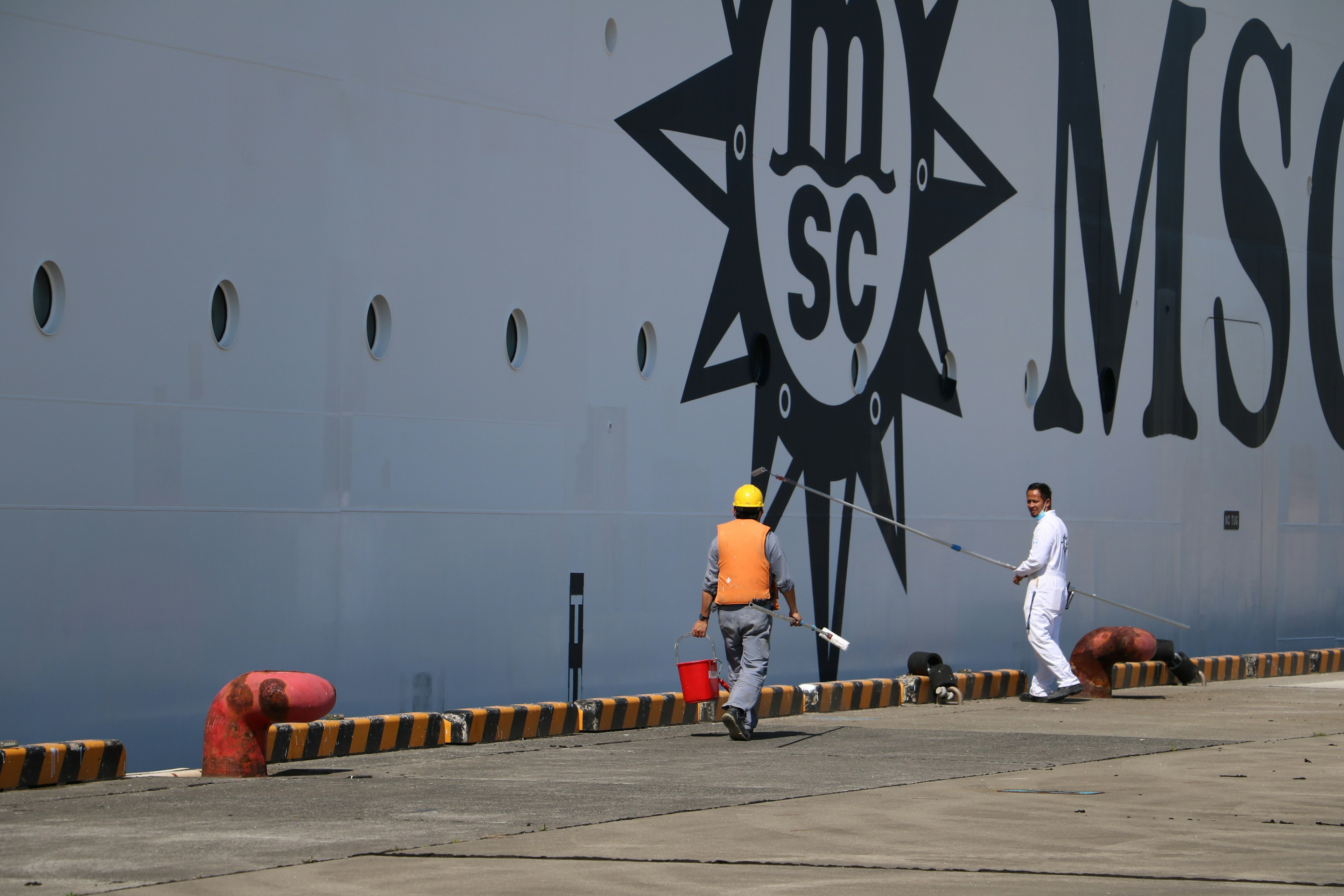 Barco MSC atracado con trabajadores en uniformes naranja y blanco