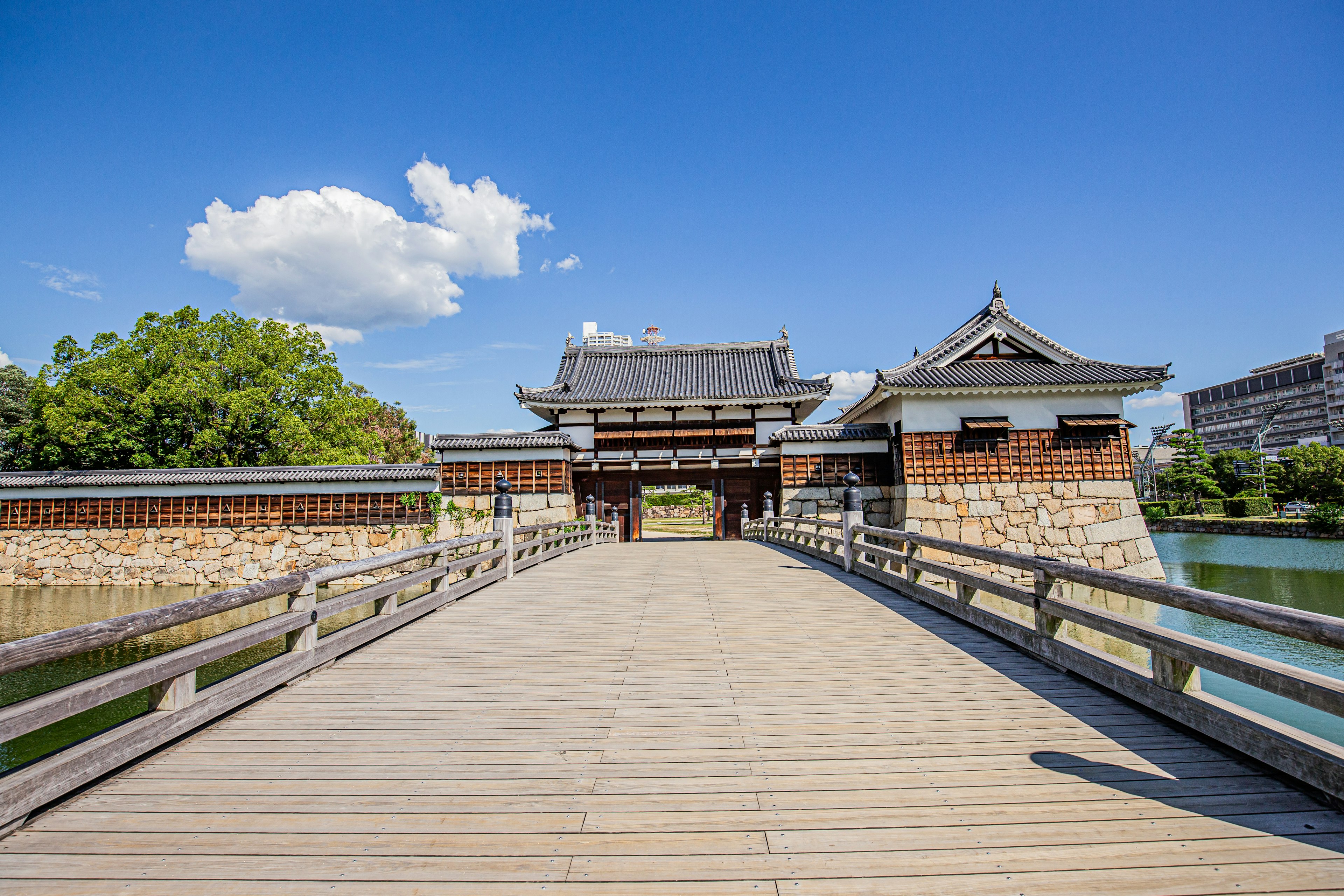 Entrada de castillo japonés tradicional con puente de madera bajo un cielo azul claro