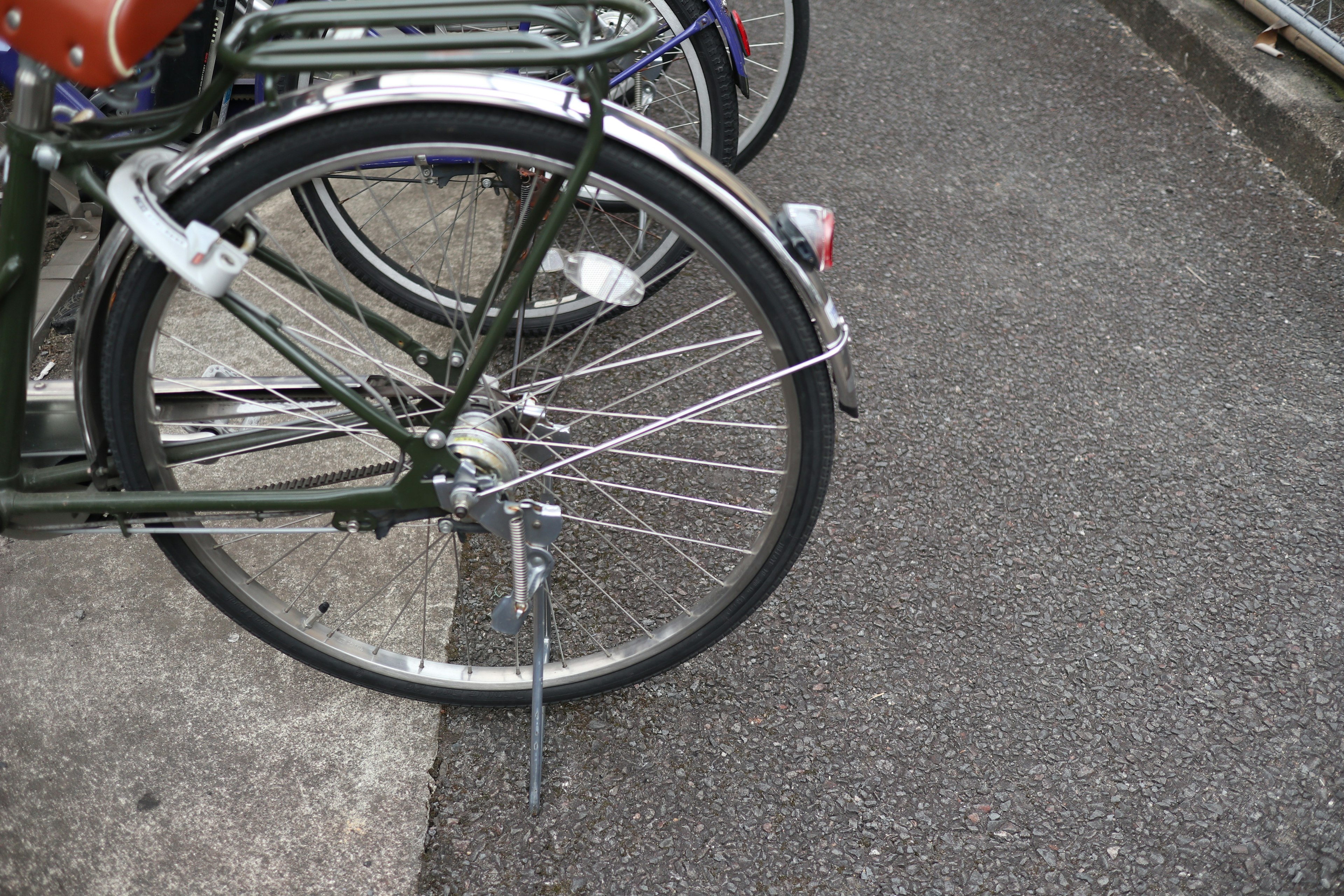 Primo piano della ruota posteriore di una bicicletta con raggi in acciaio e un telaio verde