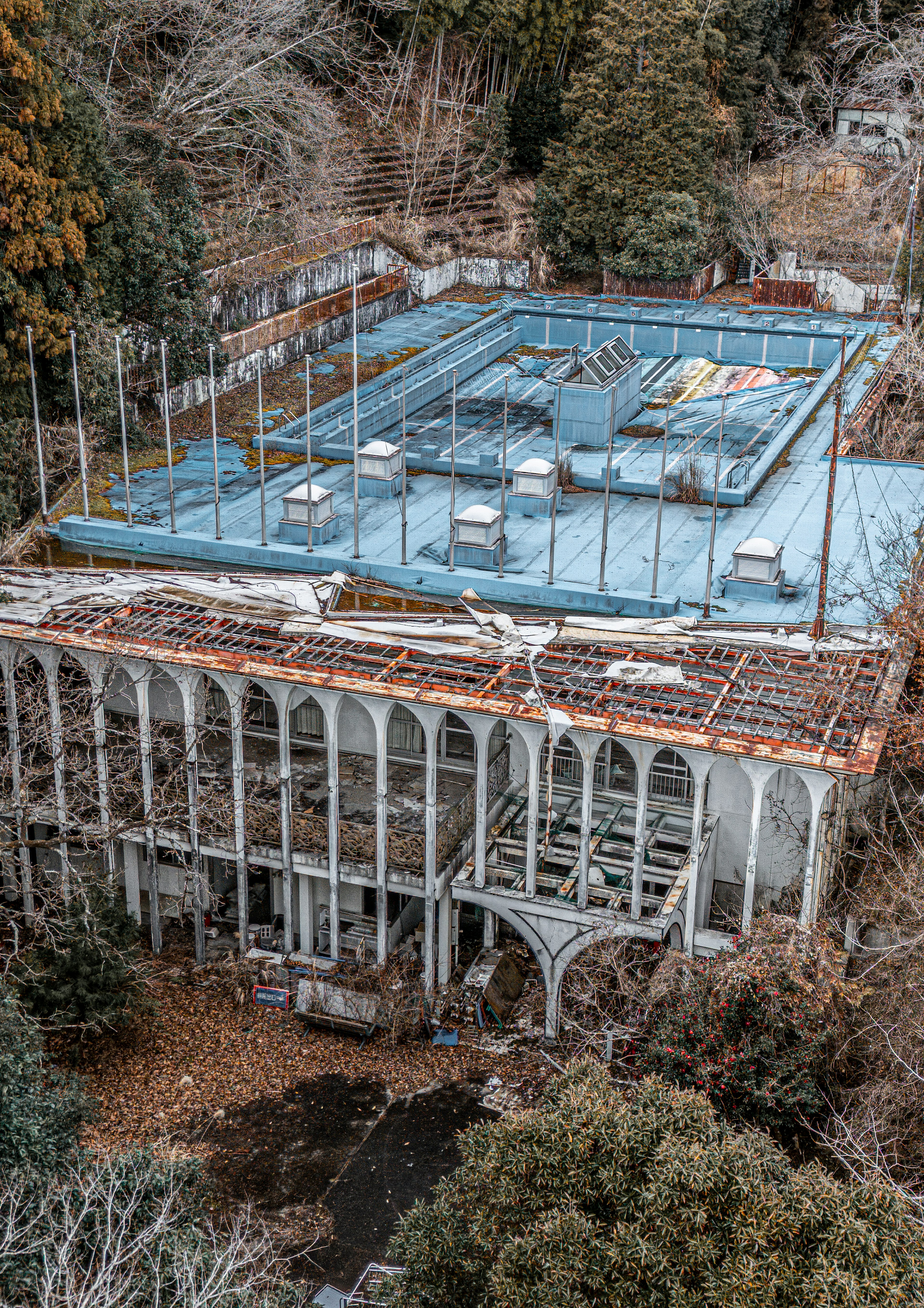 Aerial view of a dilapidated building with a tennis court