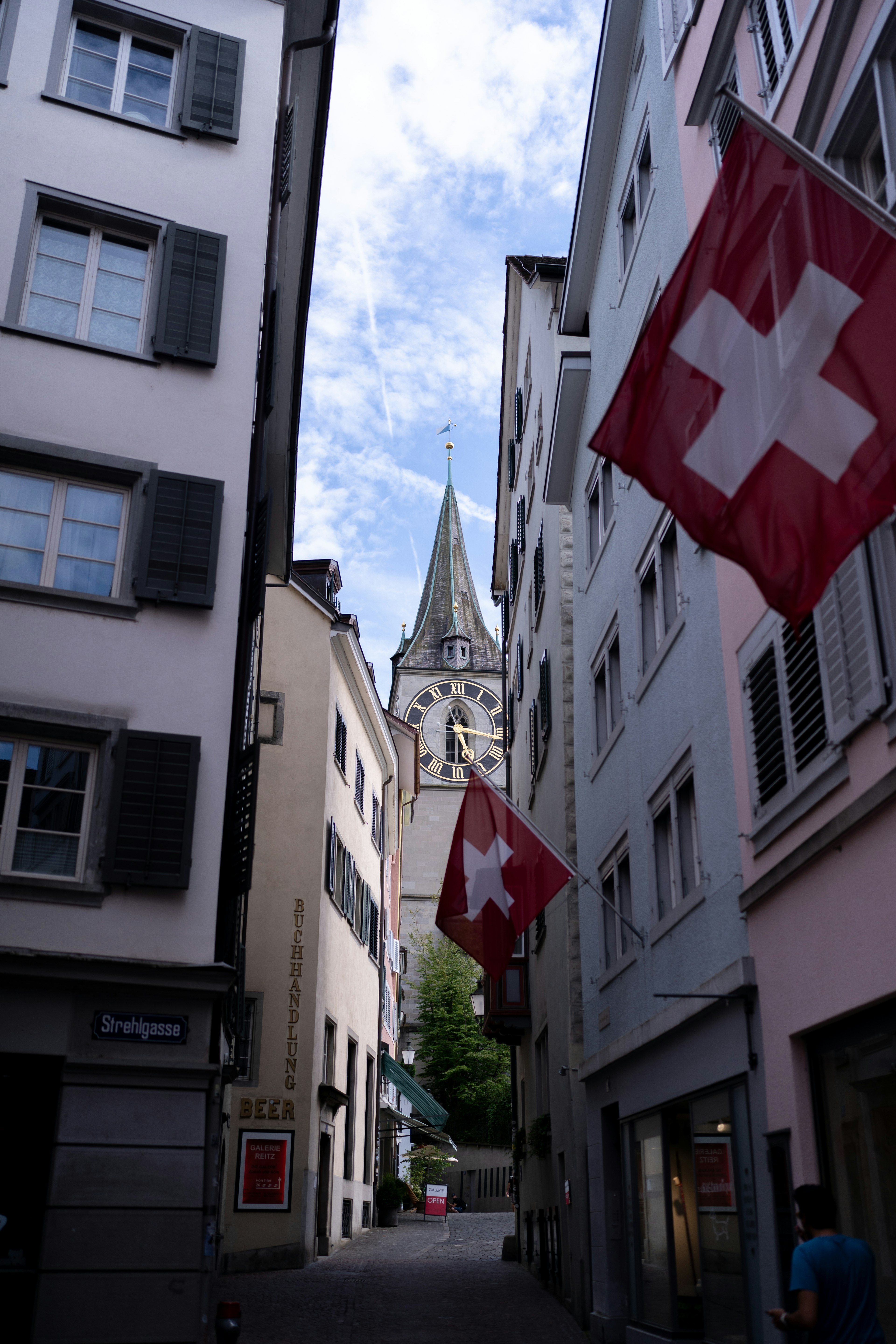 スイスの国旗が掲げられた狭い通りにある時計塔の風景