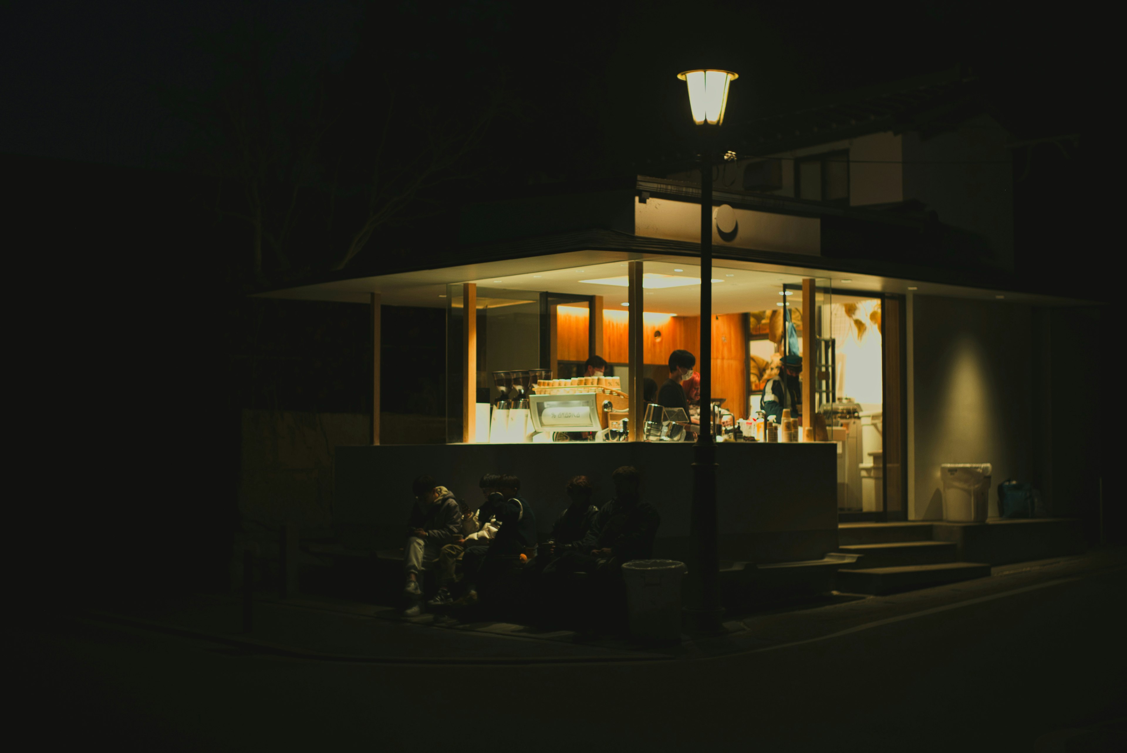 Exterior of a brightly lit cafe at night with warm lighting