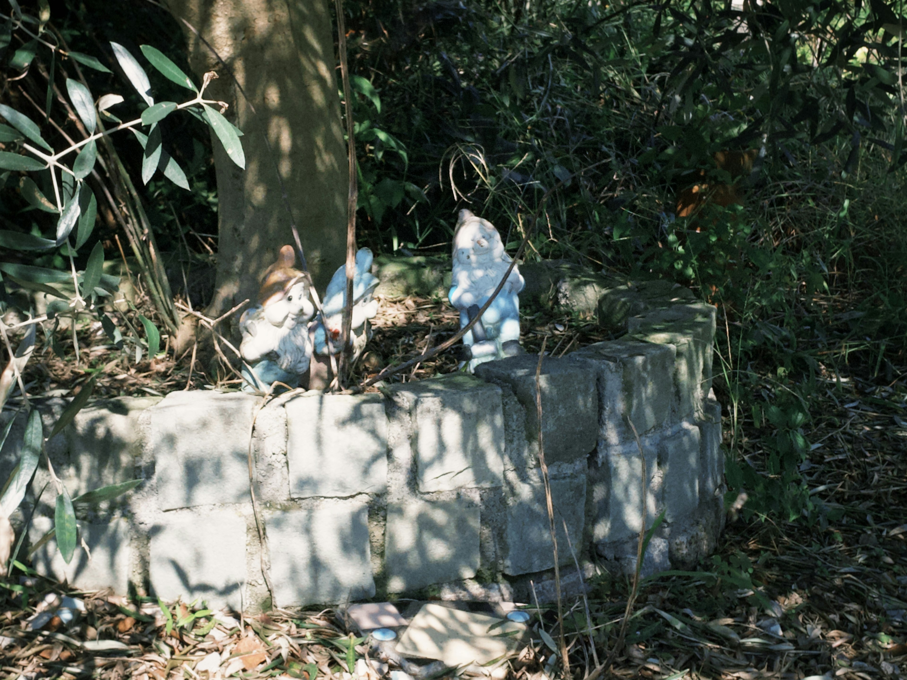 Estatuas azules rodeadas de vegetación sobre una base de piedra