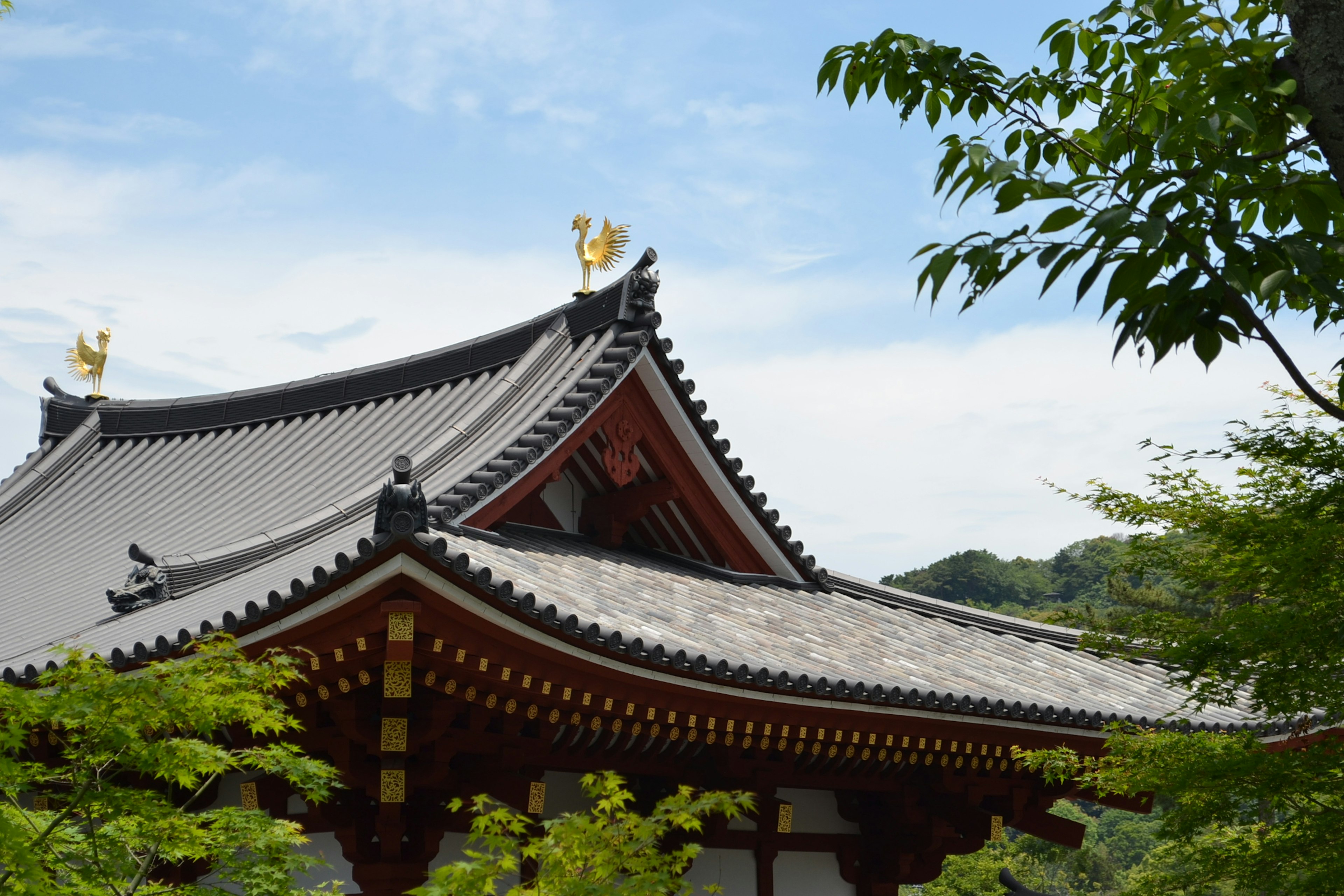 Traditional Japanese temple with ornate roof and lush greenery