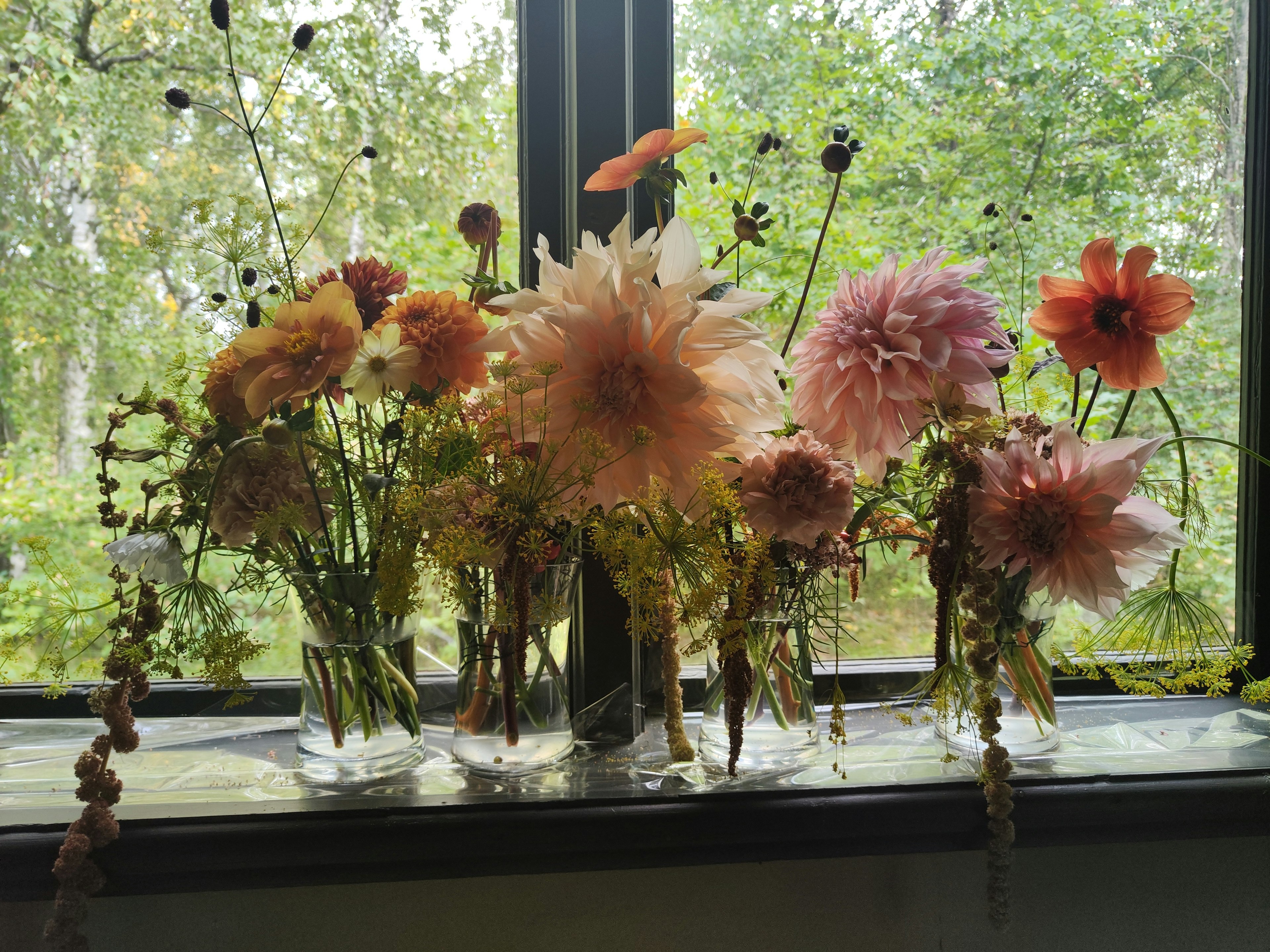 Colorful flowers arranged in vases on a bright windowsill