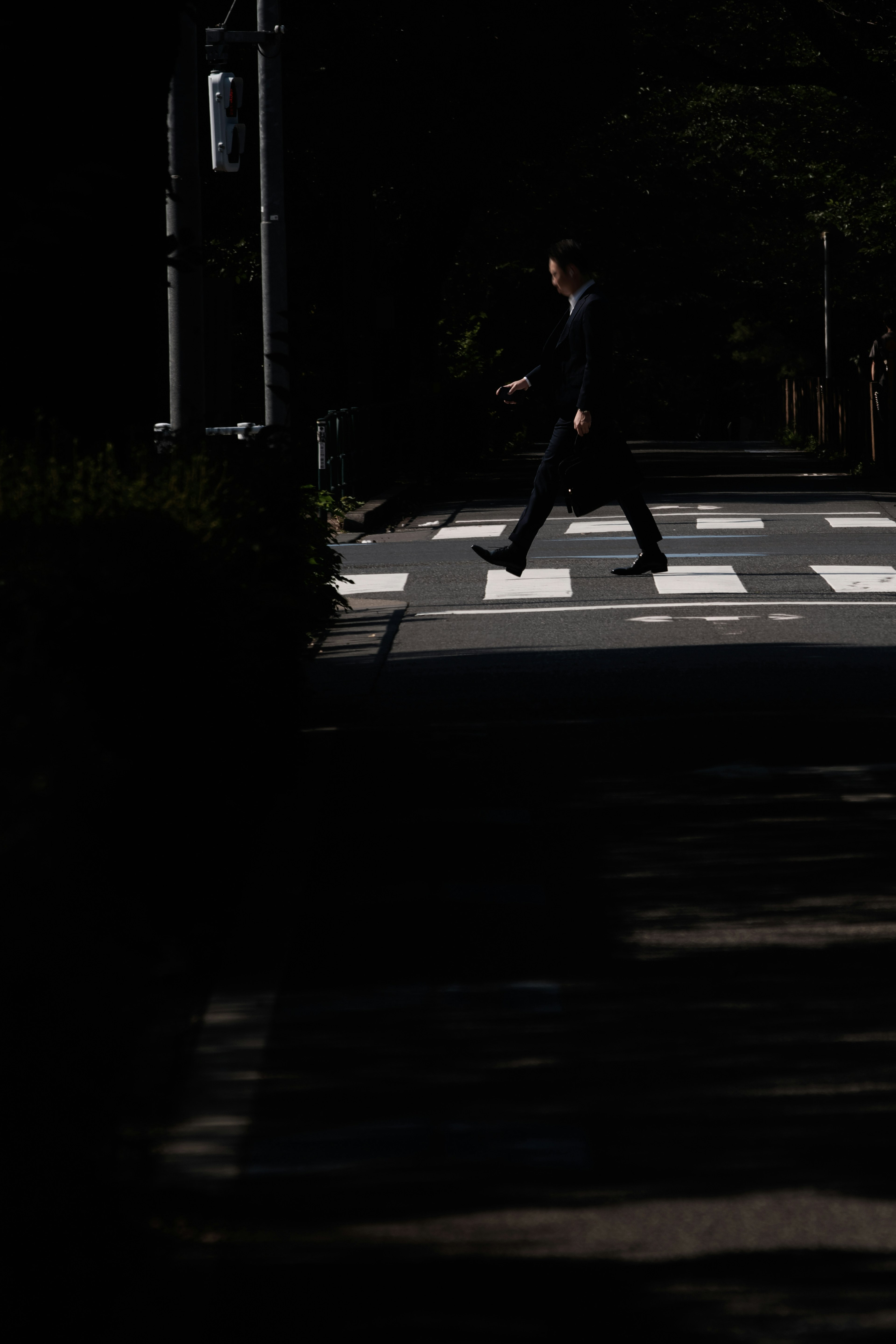 A person walking across a crosswalk against a dark background