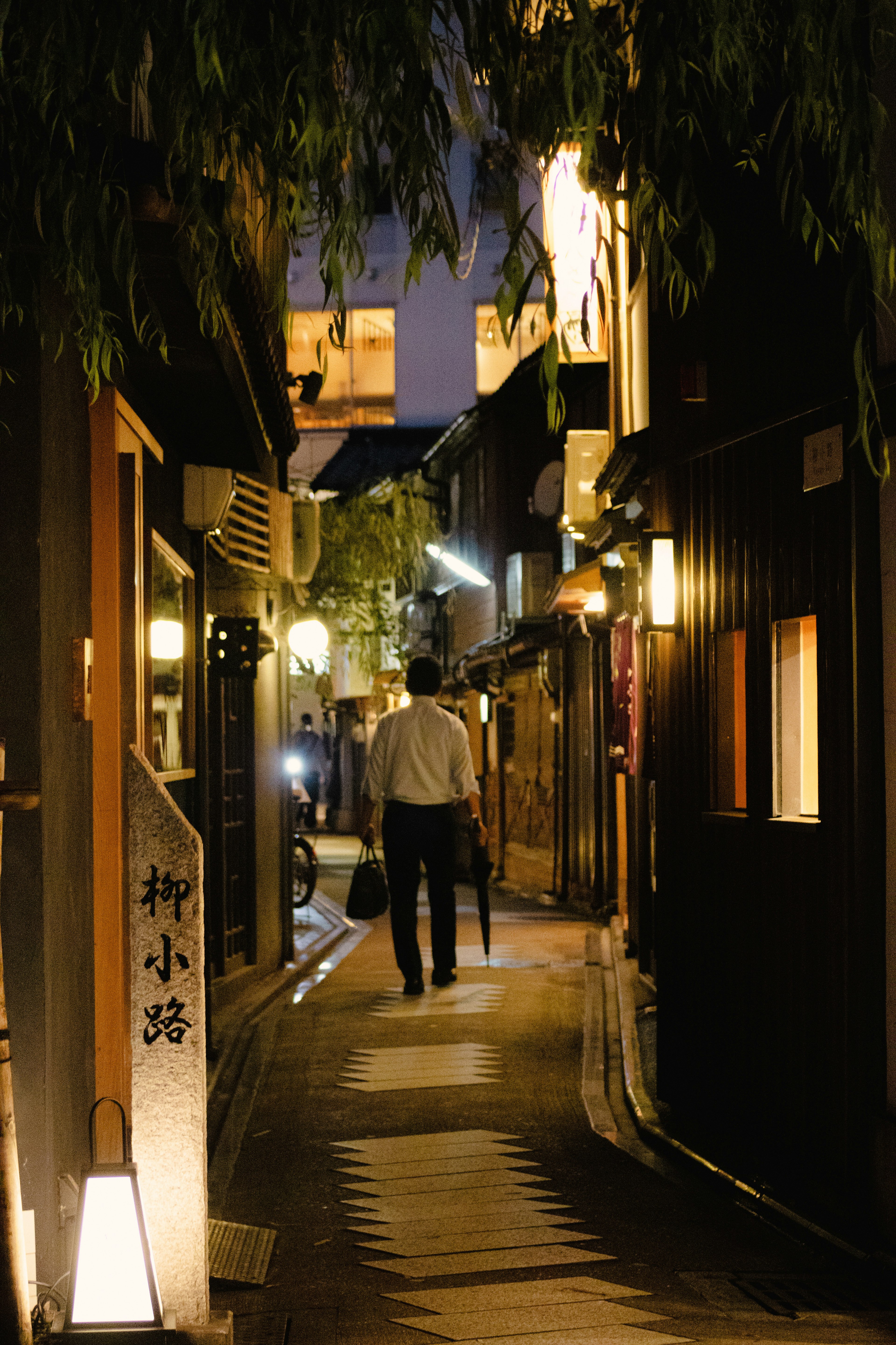 夜の小道を歩く男性と周囲の明かり