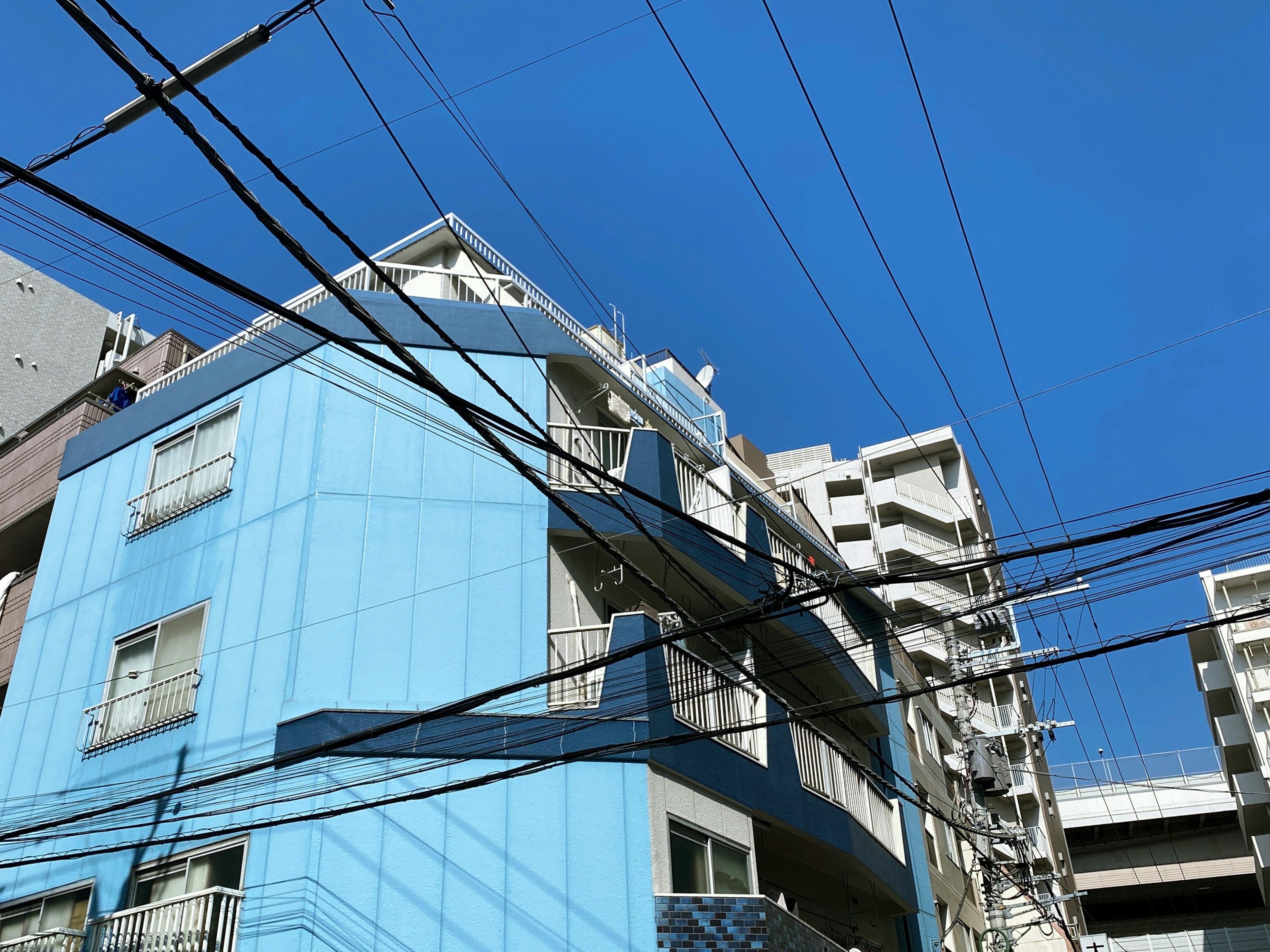 青い外壁の建物と電線がある都市の風景