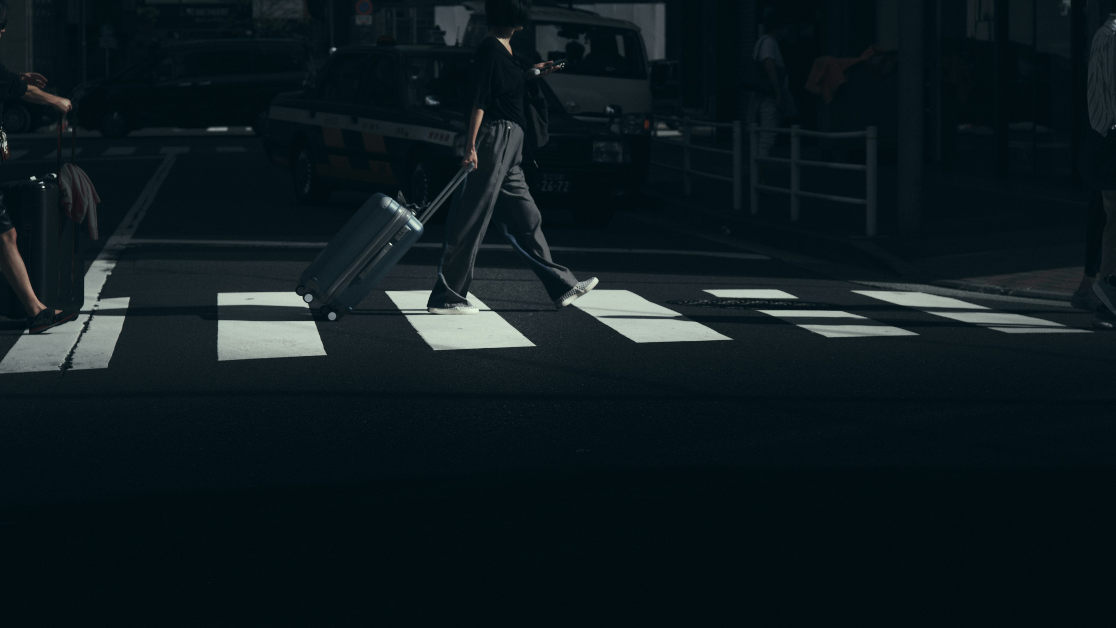 A person walking with a suitcase across a crosswalk