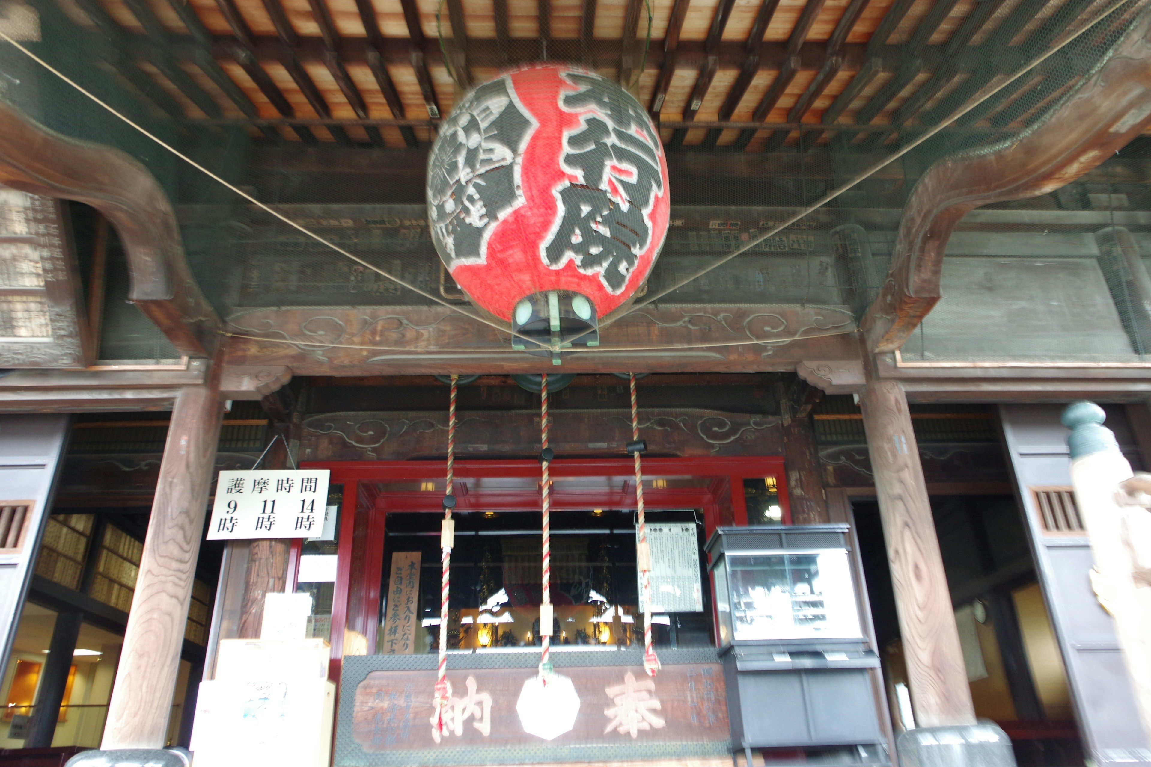 Entrée d'un bâtiment japonais traditionnel avec une lanterne rouge suspendue et une structure en bois