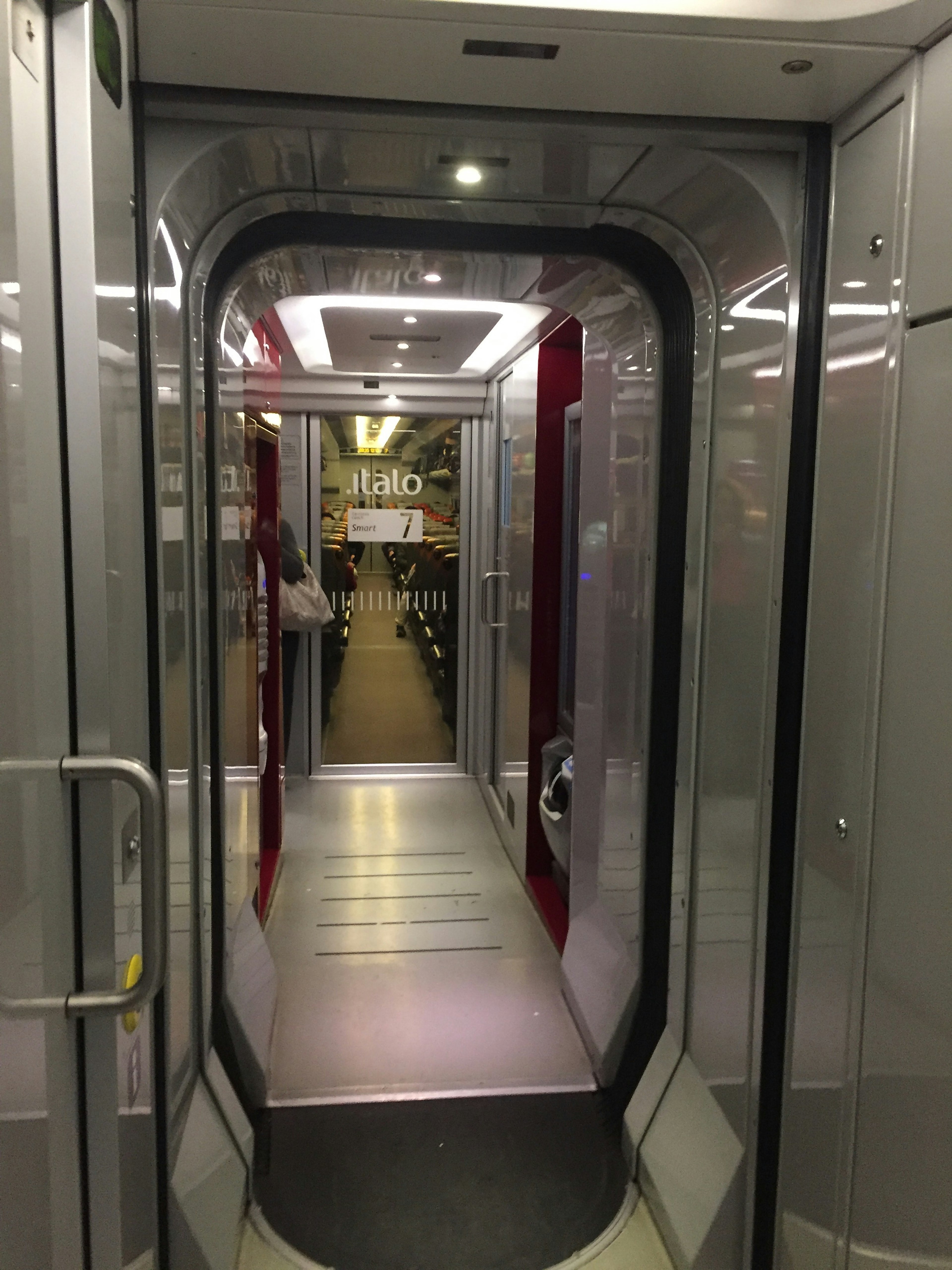 Vue intérieure d'un couloir de train moderne avec éclairage lumineux et finition métallique lisse