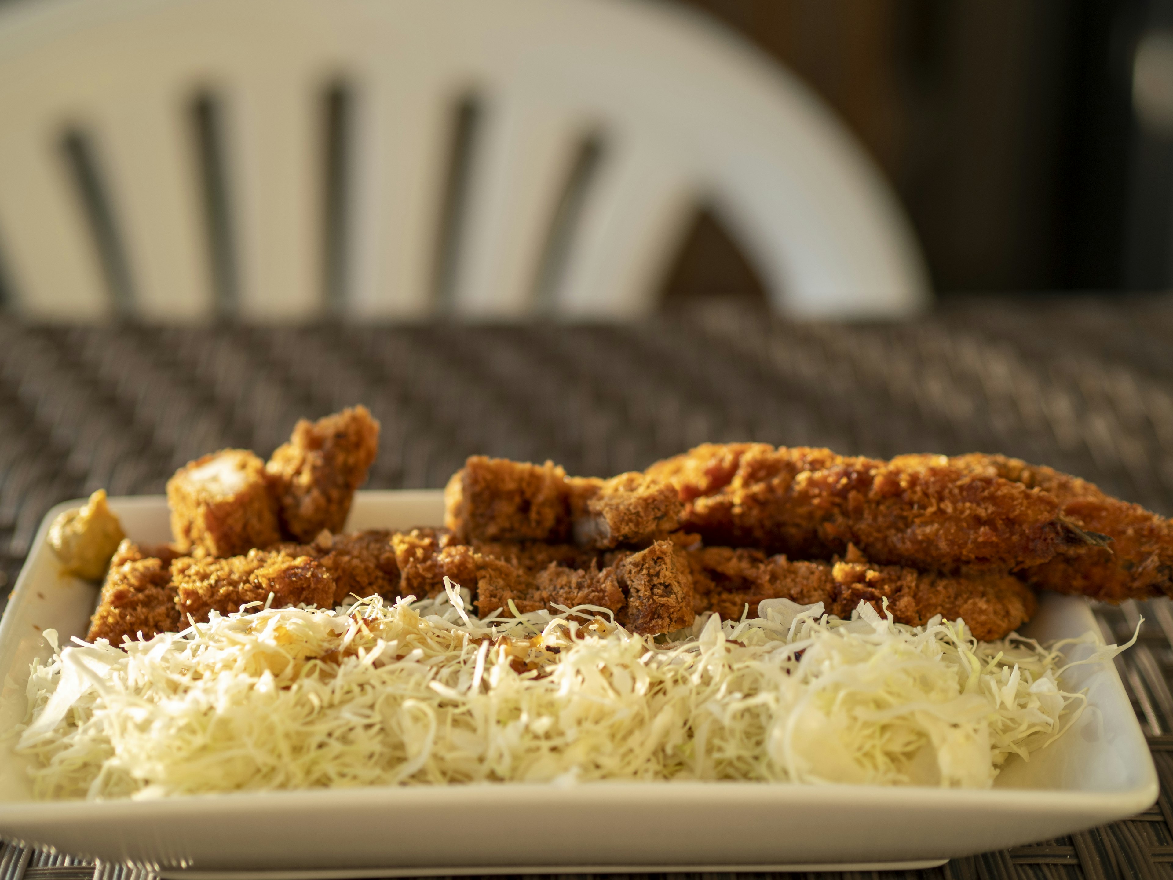 Fried fish fillets served on a white plate with shredded cabbage