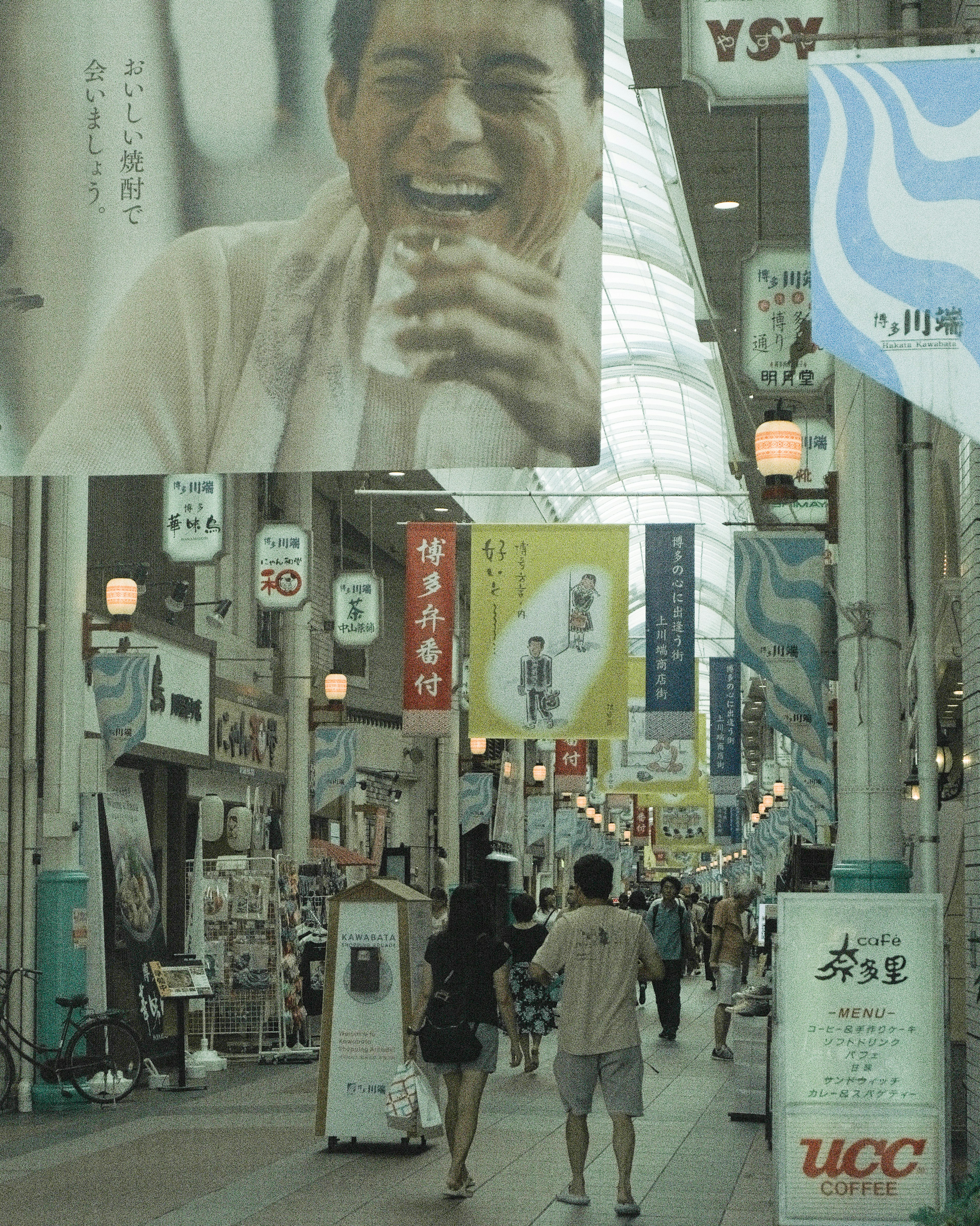 Una calle comercial concurrida con grandes pancartas y personas caminando