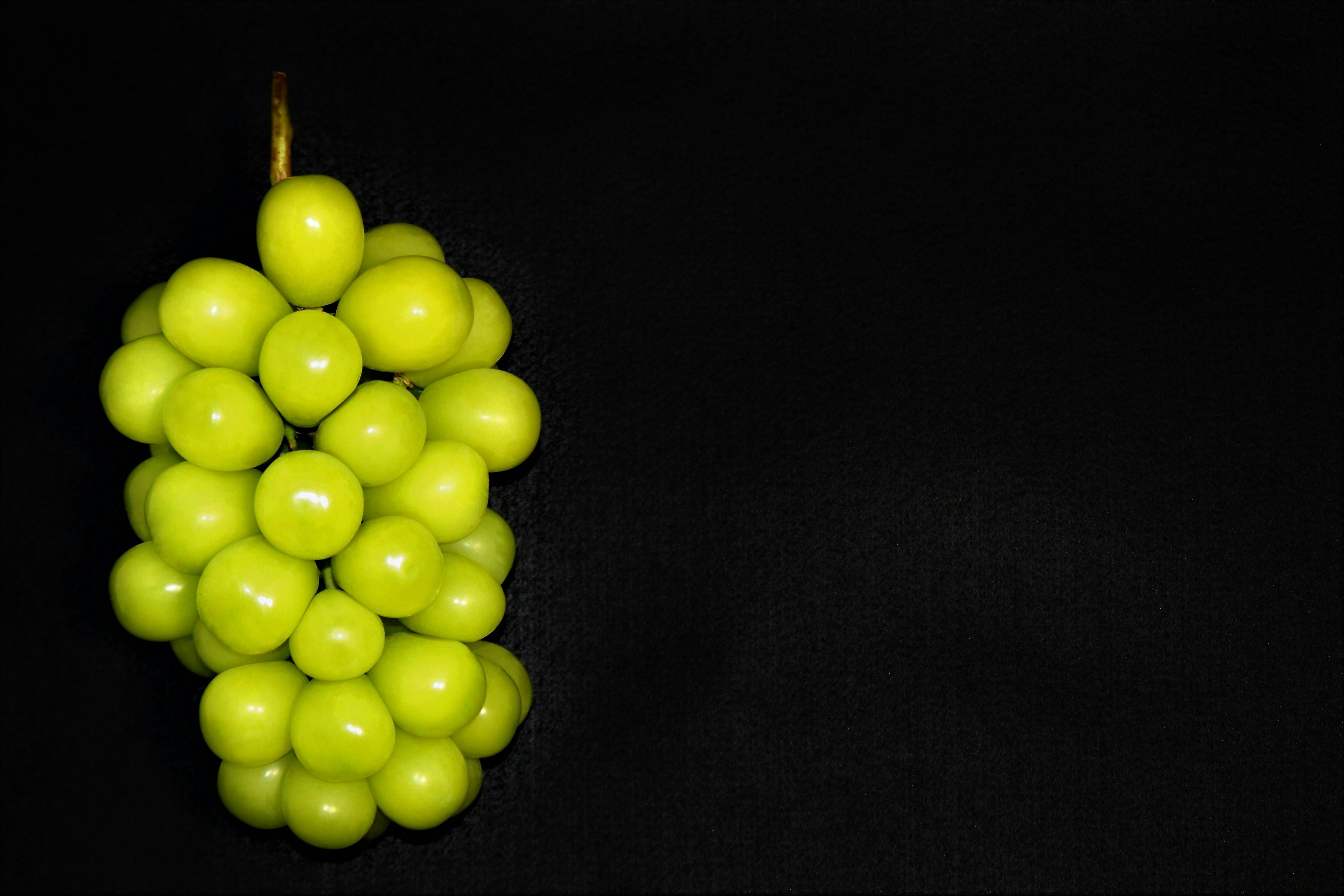 Un racimo de uvas verdes sobre un fondo negro