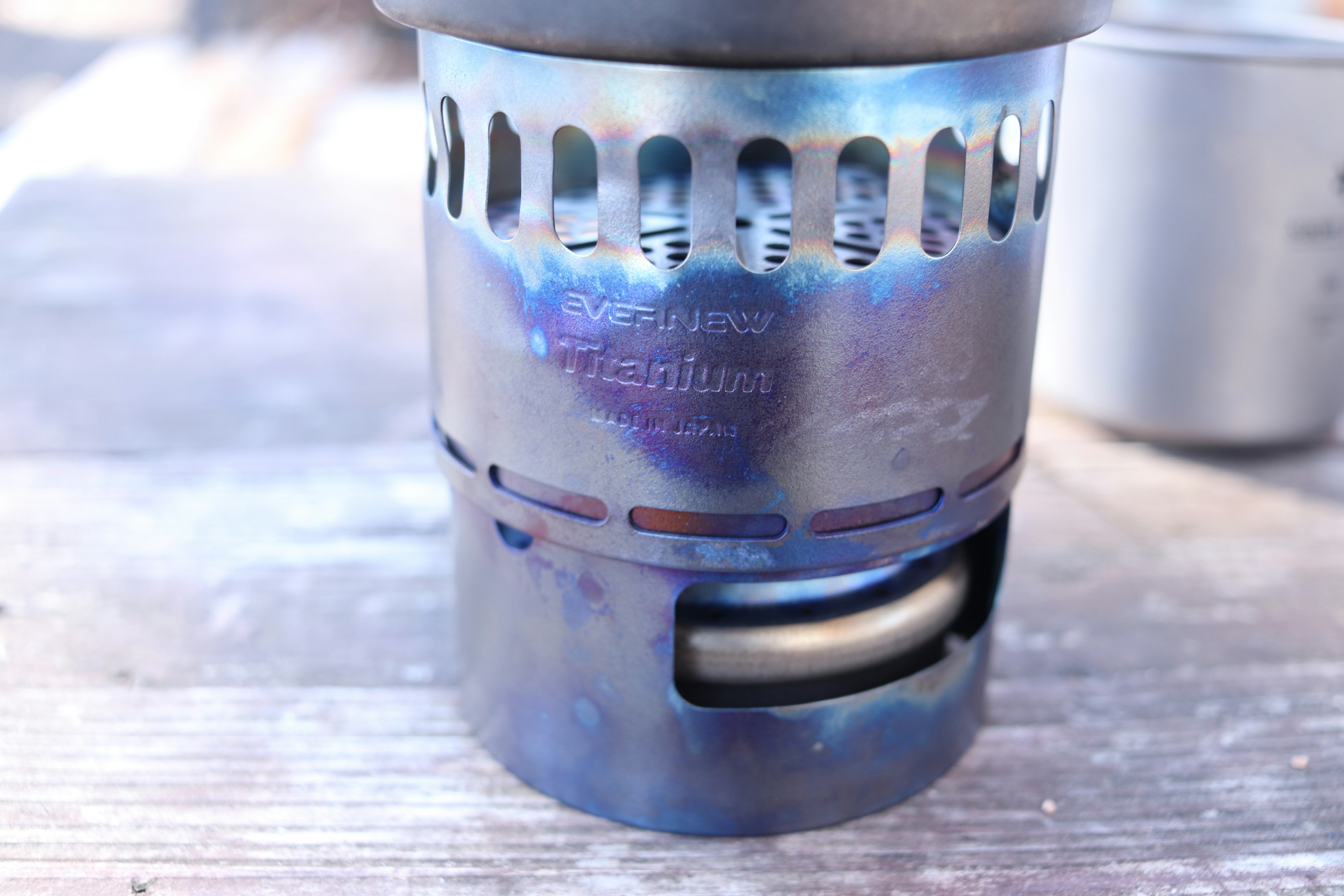 Metal camping stove with blue and purple hues featuring engraved markings