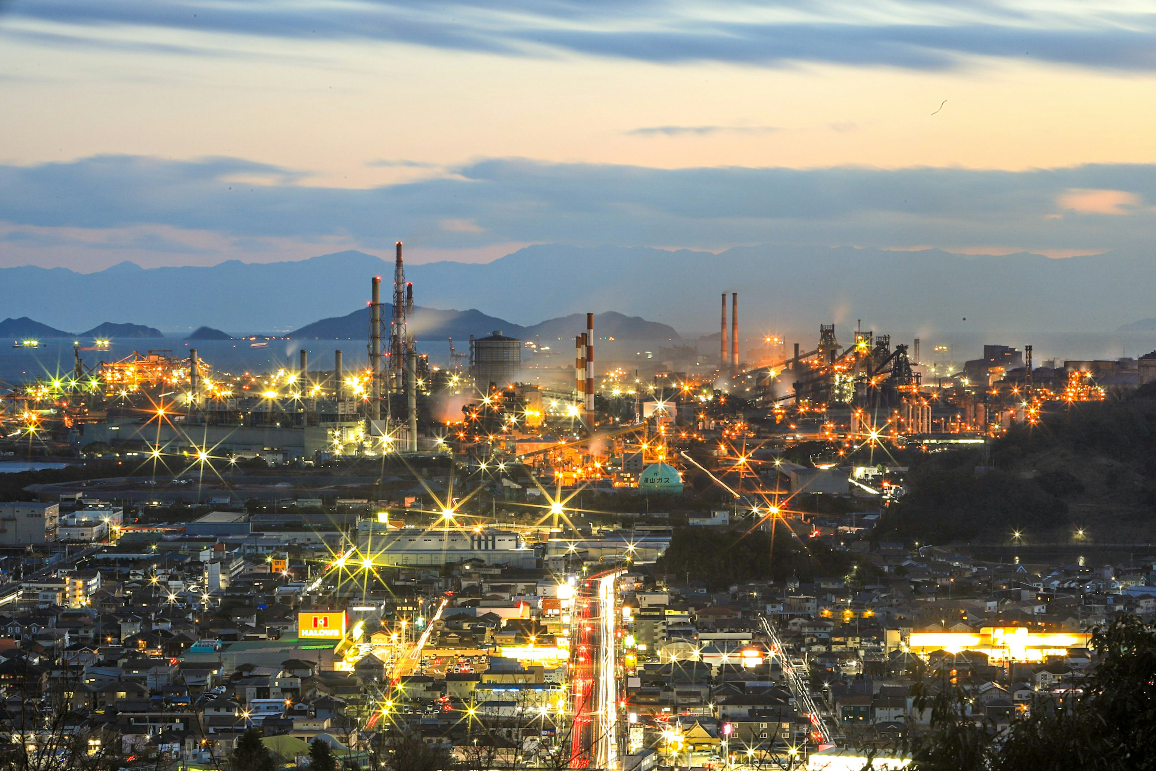 Paisaje industrial al atardecer con luces brillantes de fábricas y chimeneas