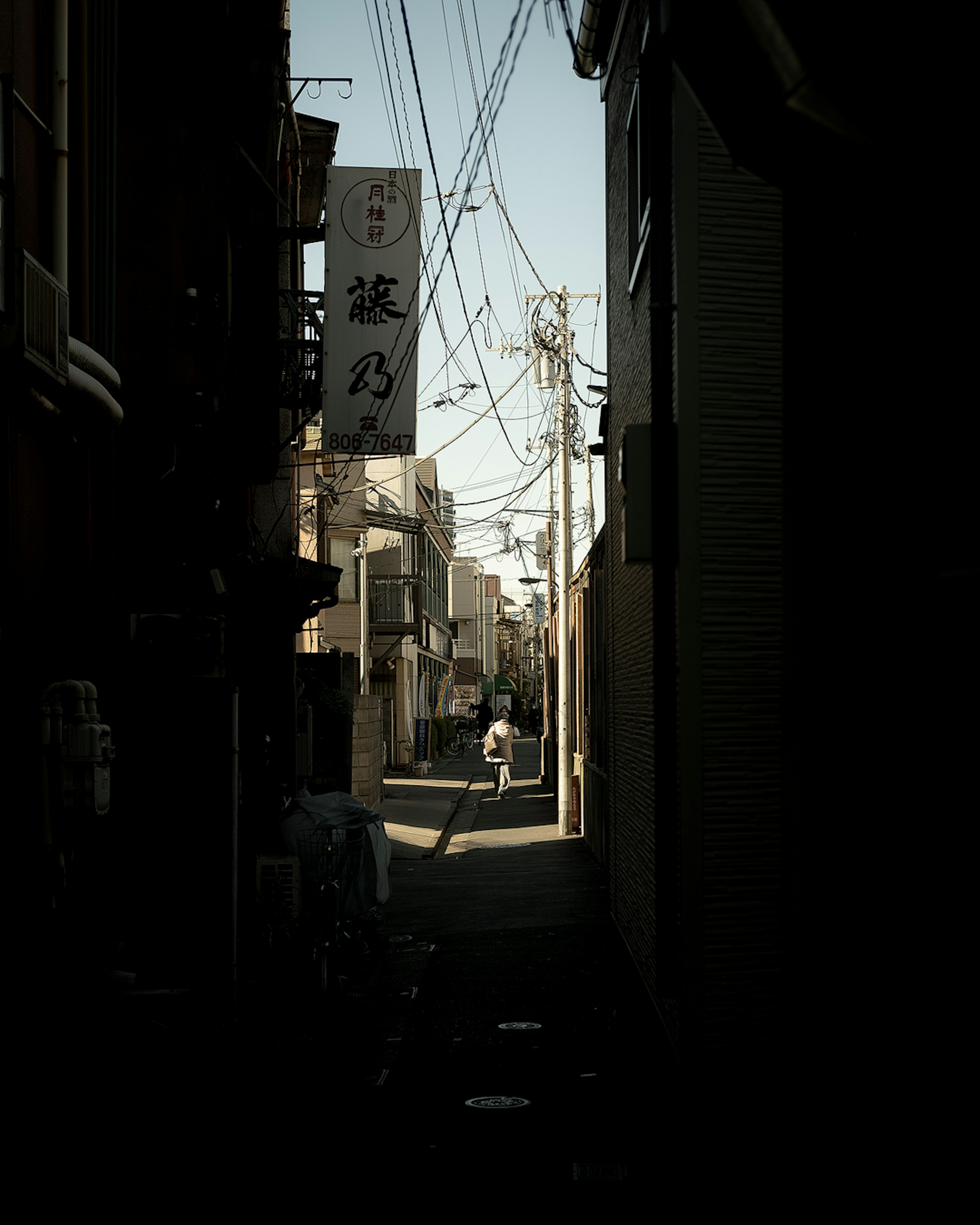 Schmale Gasse mit der Silhouette einer Person und Stromleitungen