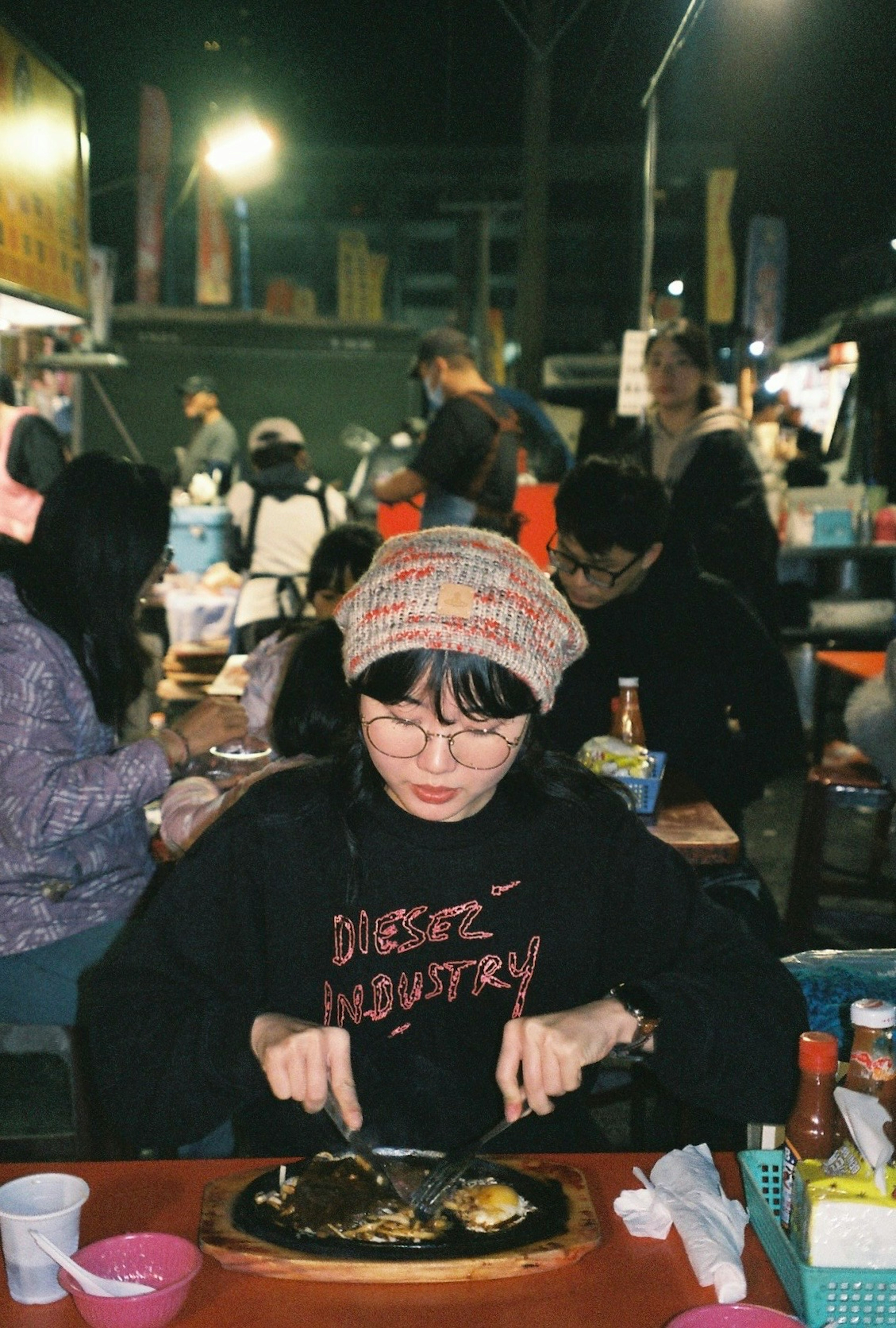 Mujer disfrutando de una comida en un puesto de comida callejera con una diadema