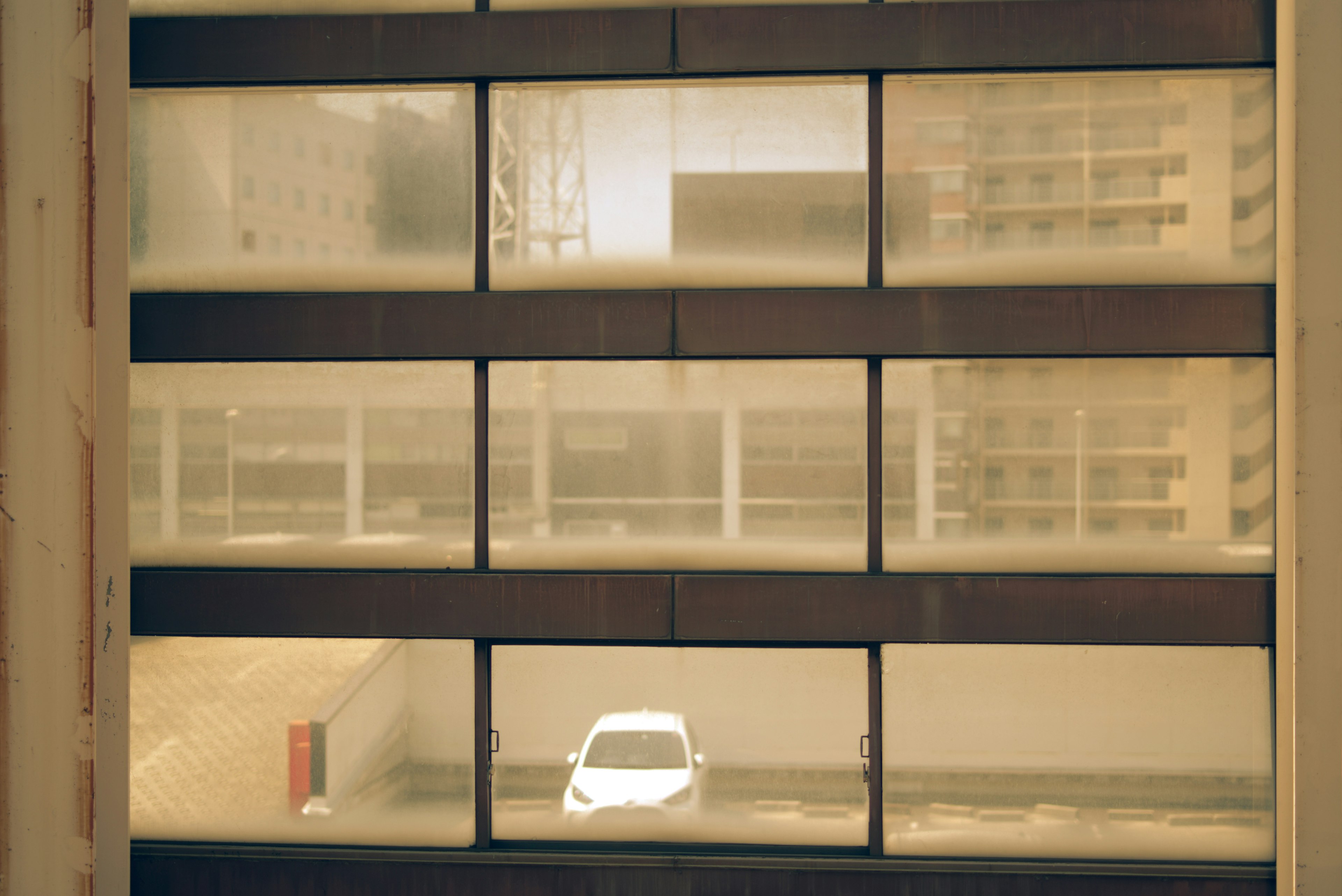 Vue d'un parking à travers une fenêtre avec une voiture blanche