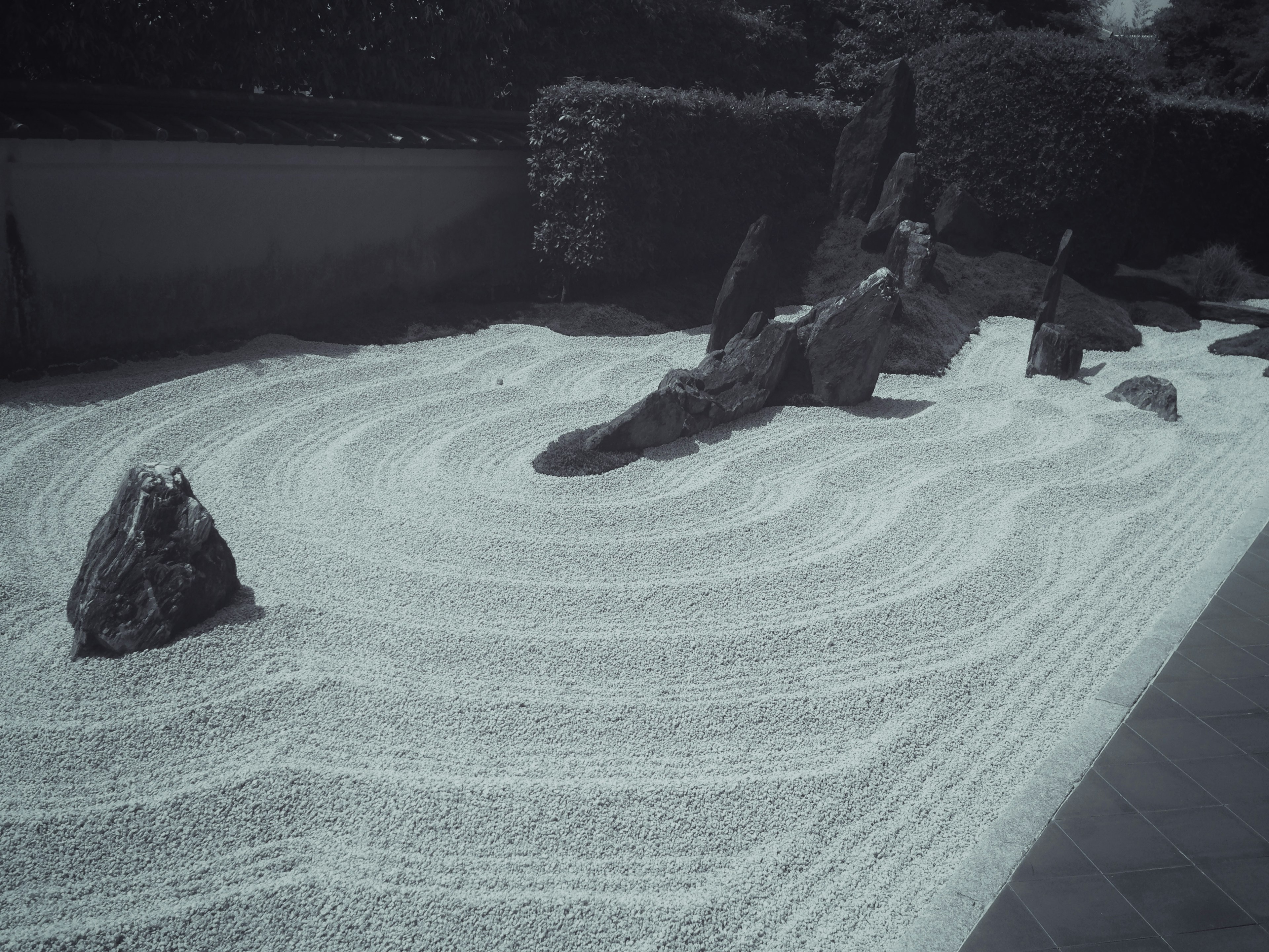 Jardin zen avec du sable blanc et des pierres créant des motifs en ondulations