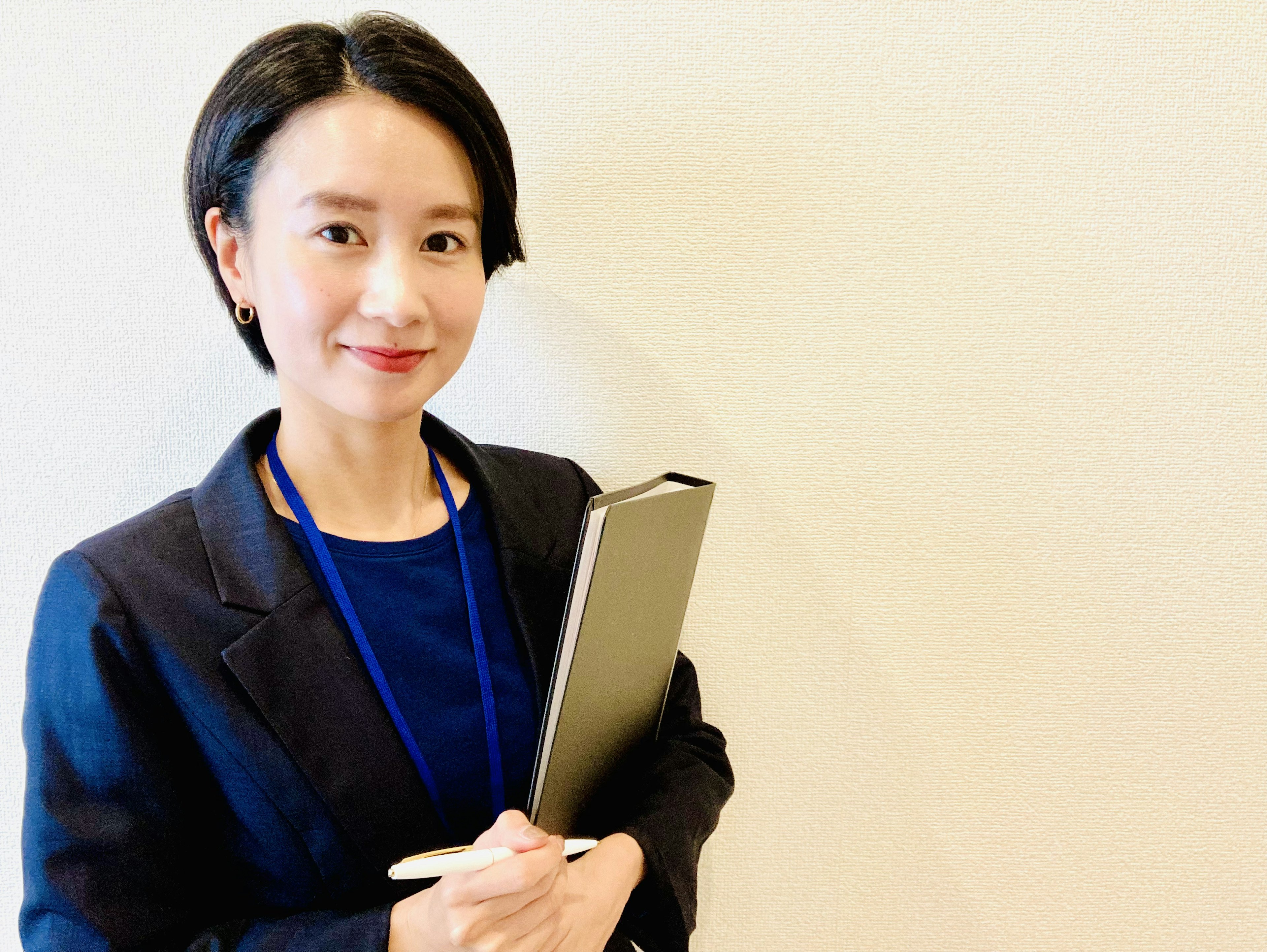 A woman in a business suit holding a notebook with a smile