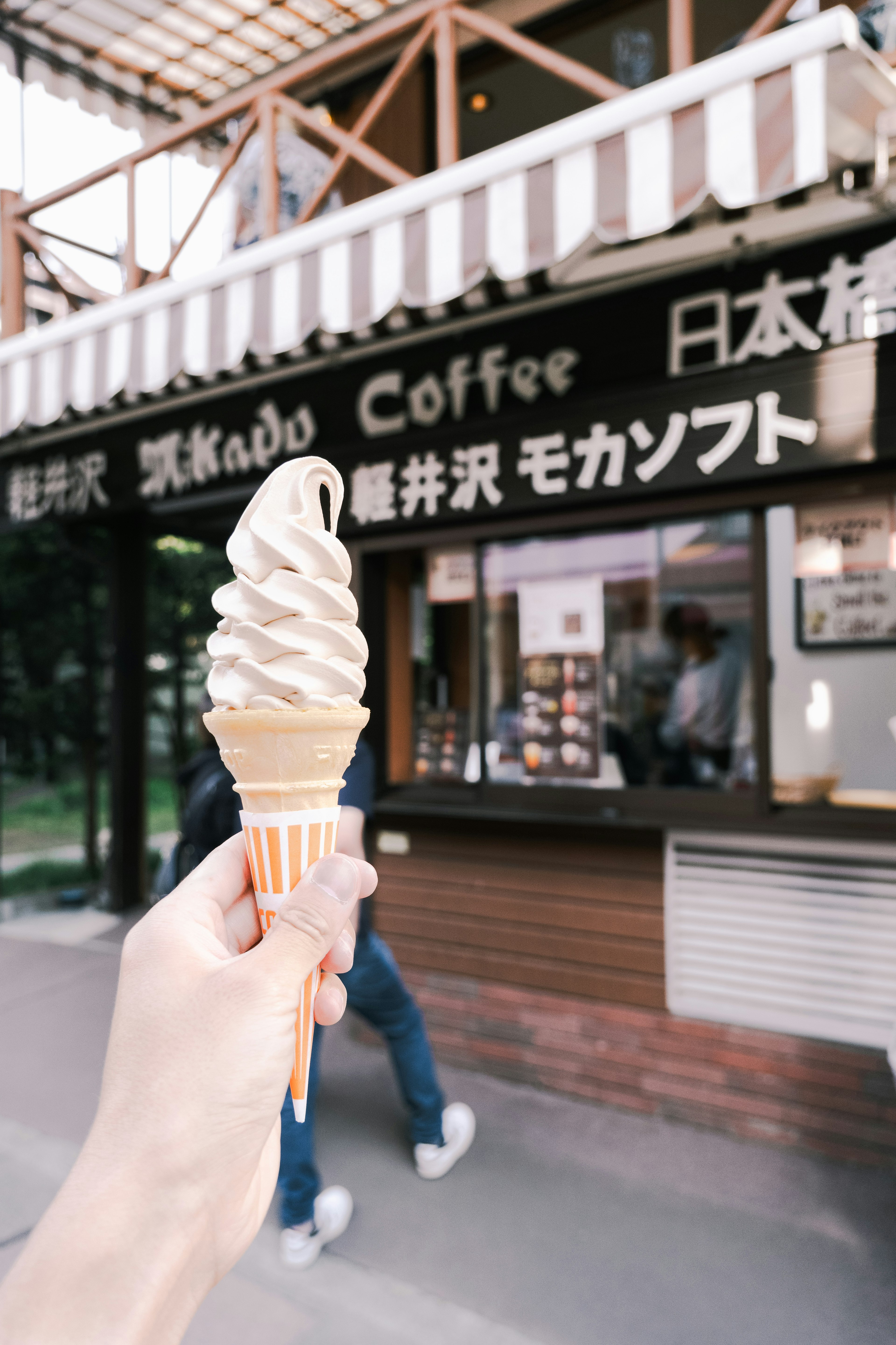 Main tenant une glace soft en face d'un café