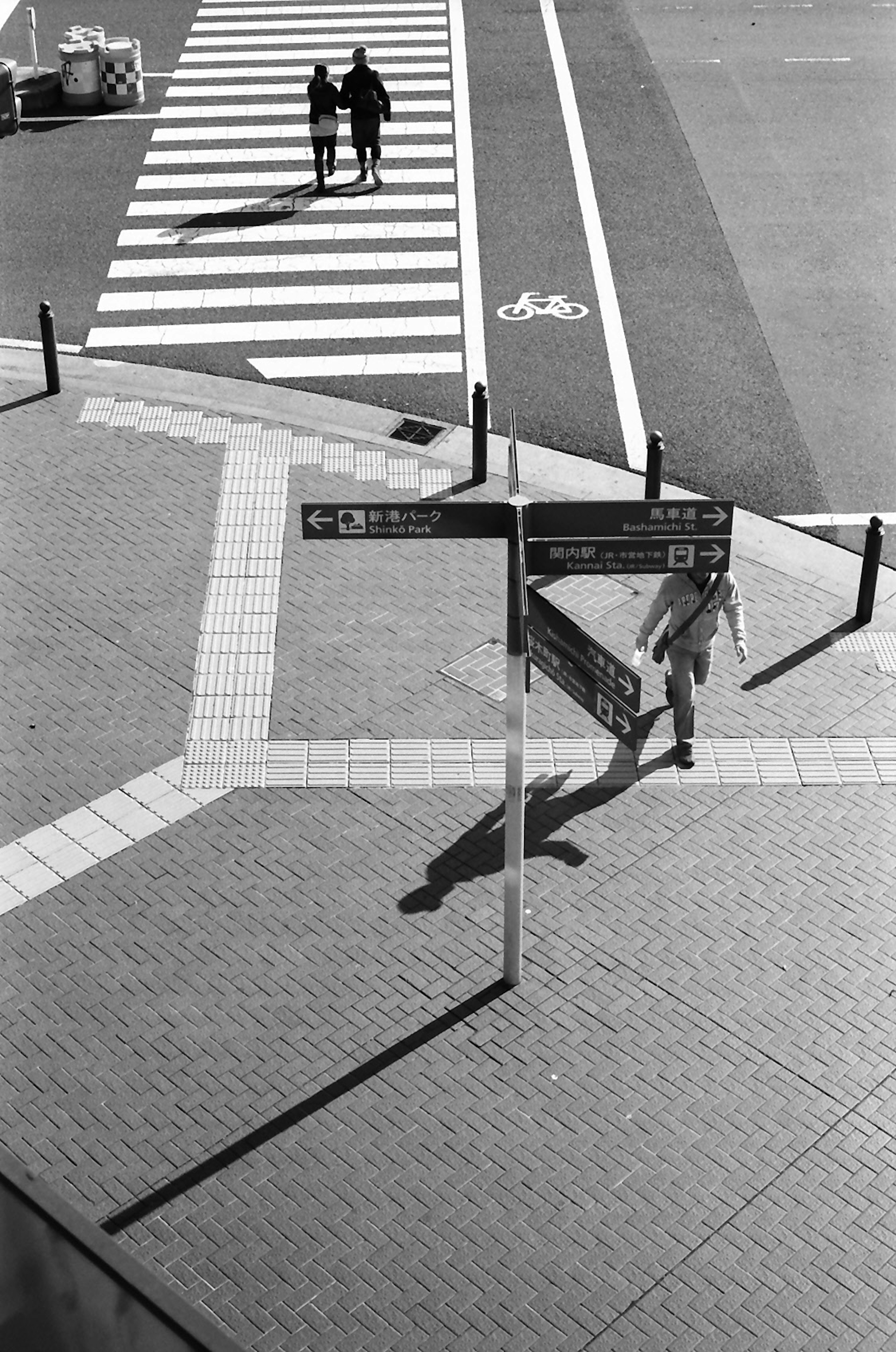 Schwarzweißbild von Fußgängern an einem Zebrastreifen mit Straßenschildern