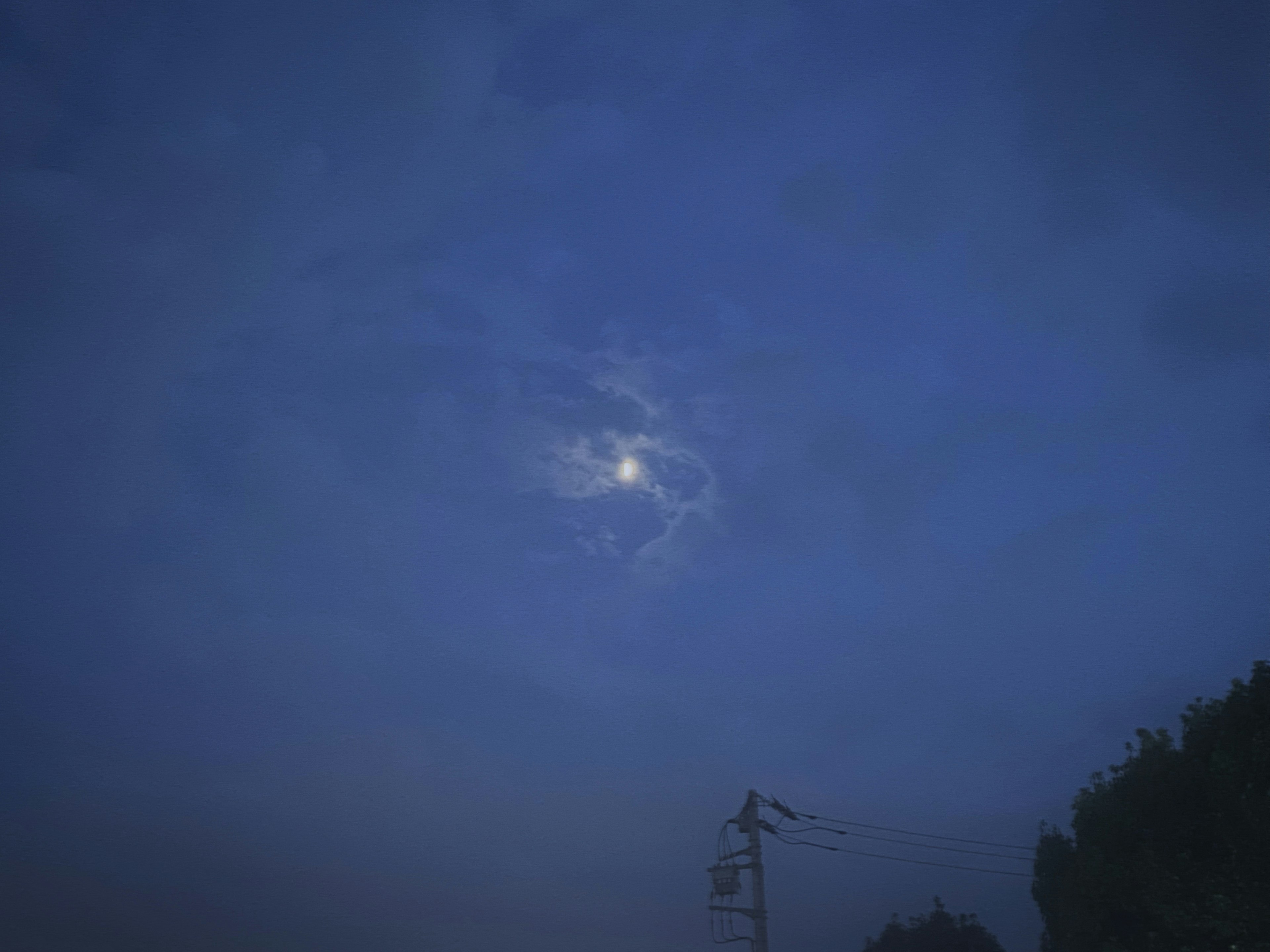 Luna parcialmente oculta por nubes en un cielo azul