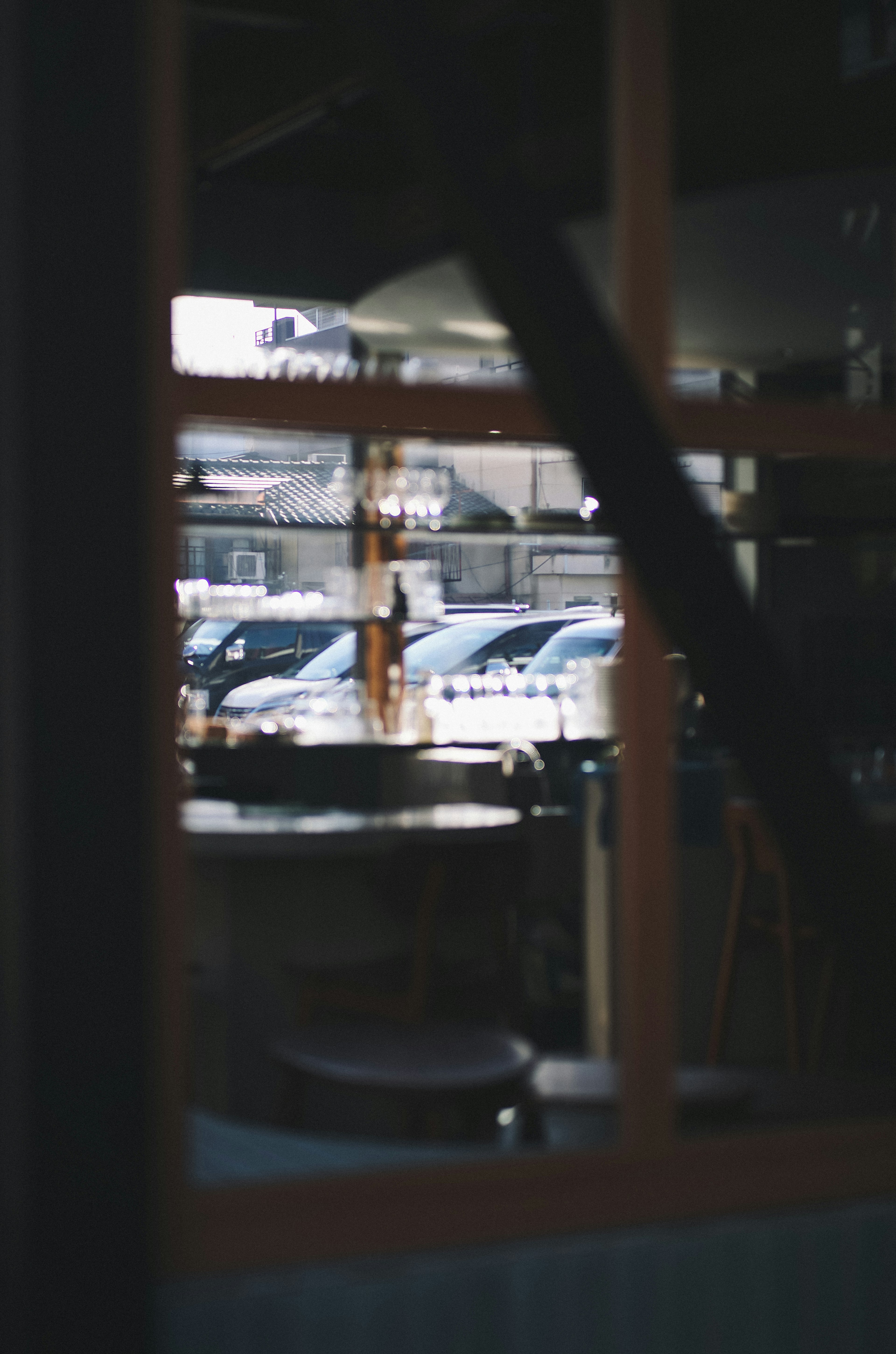 View through a window showing parked cars and a table