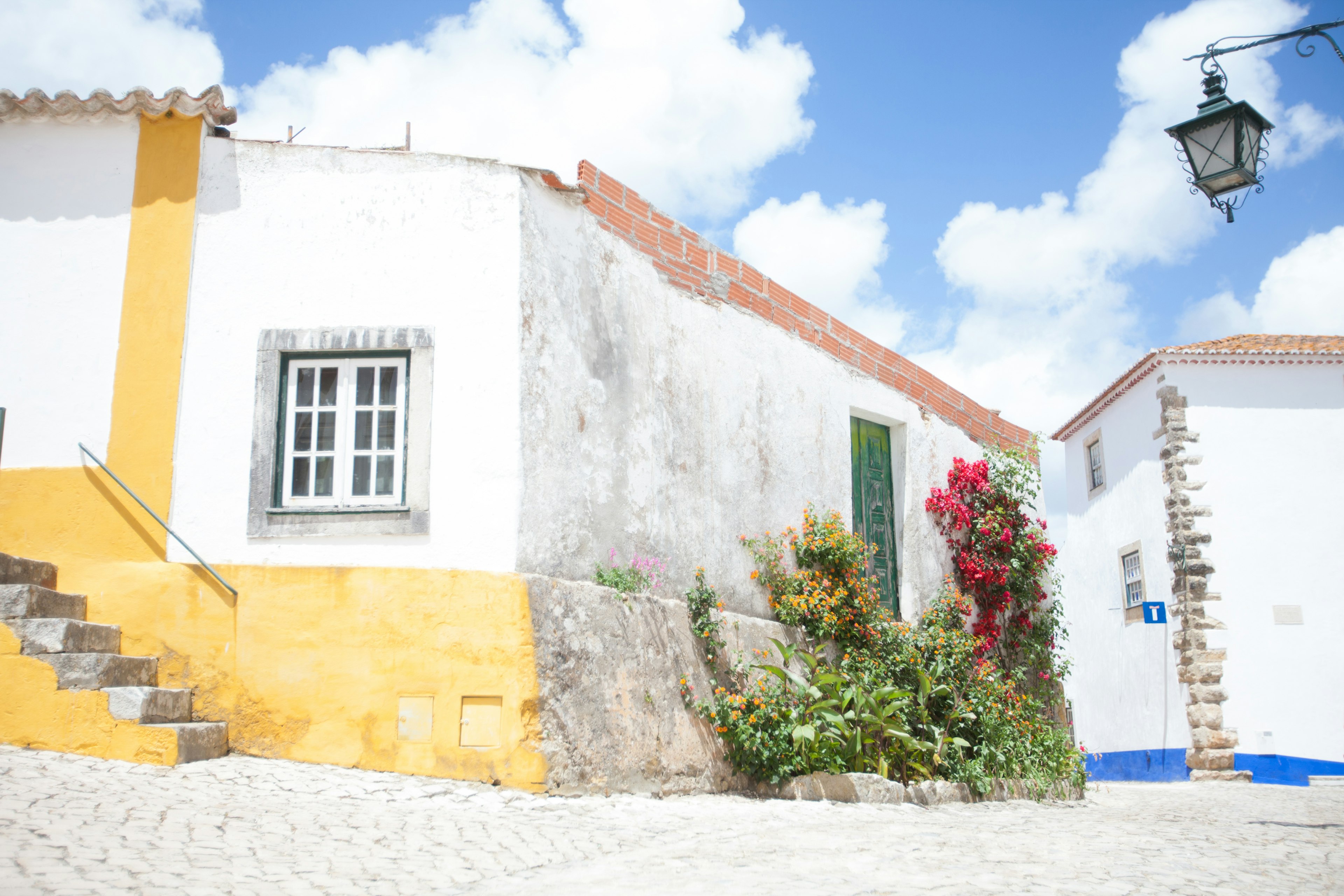 Casa blanca con acentos amarillos y flores en flor bajo un cielo brillante