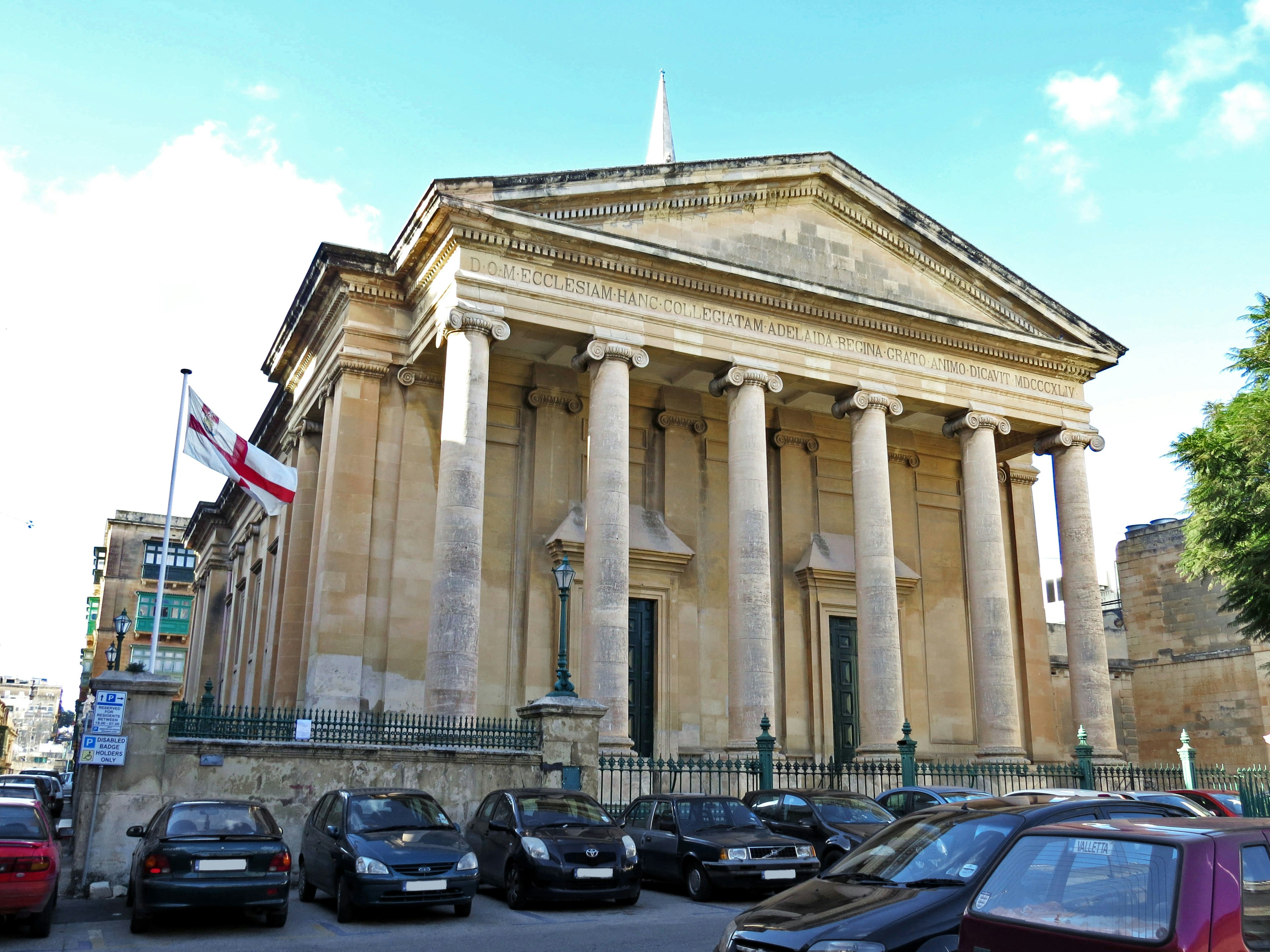 Historisches Gebäude mit großen Säulen und Parkplatz