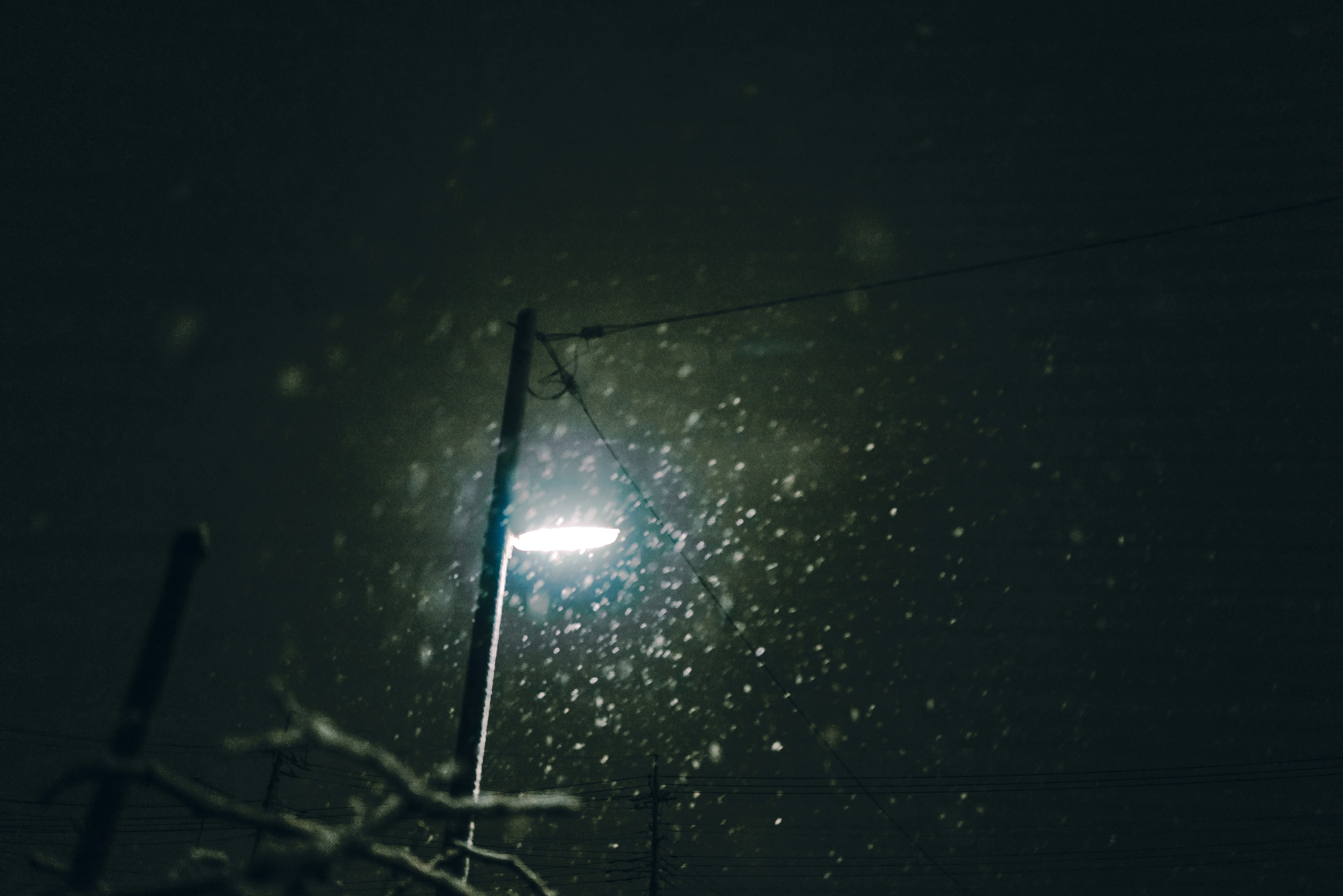 Lampadaire éclairant la neige qui tombe la nuit