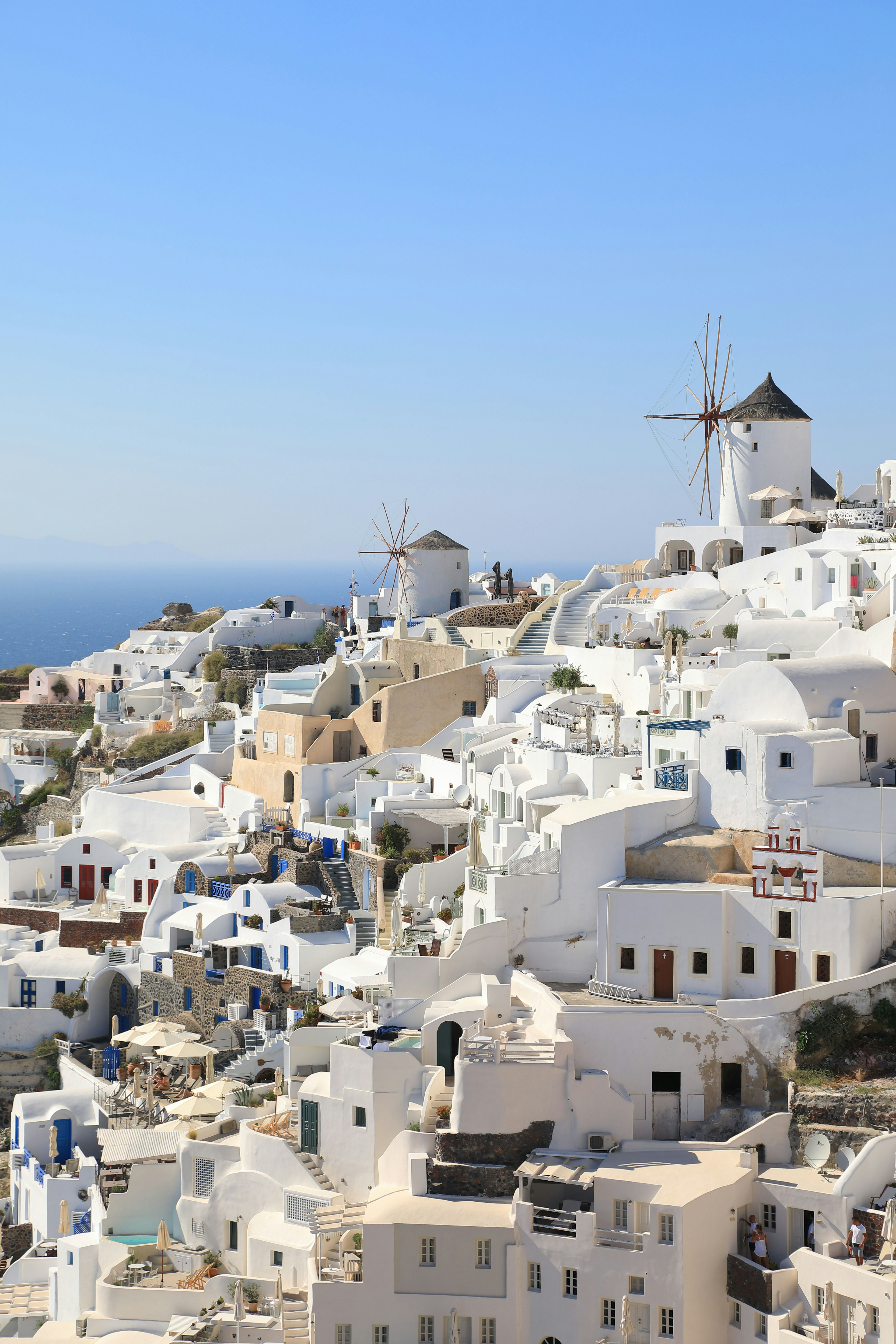 Vue panoramique de Santorin avec des maisons blanches et un moulin à vent surplombant la mer bleue