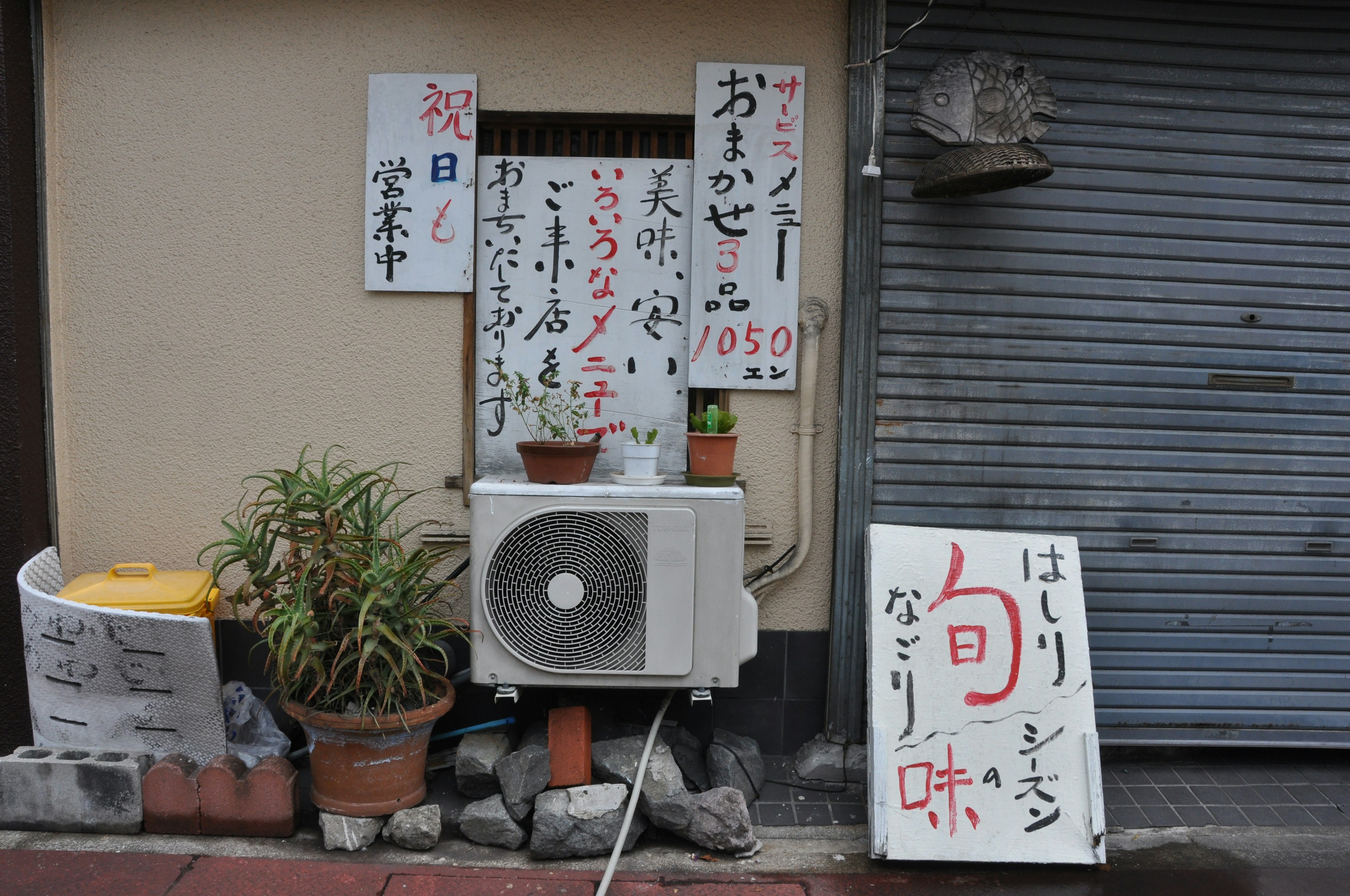 Exterior view of a shop displaying menus and plants