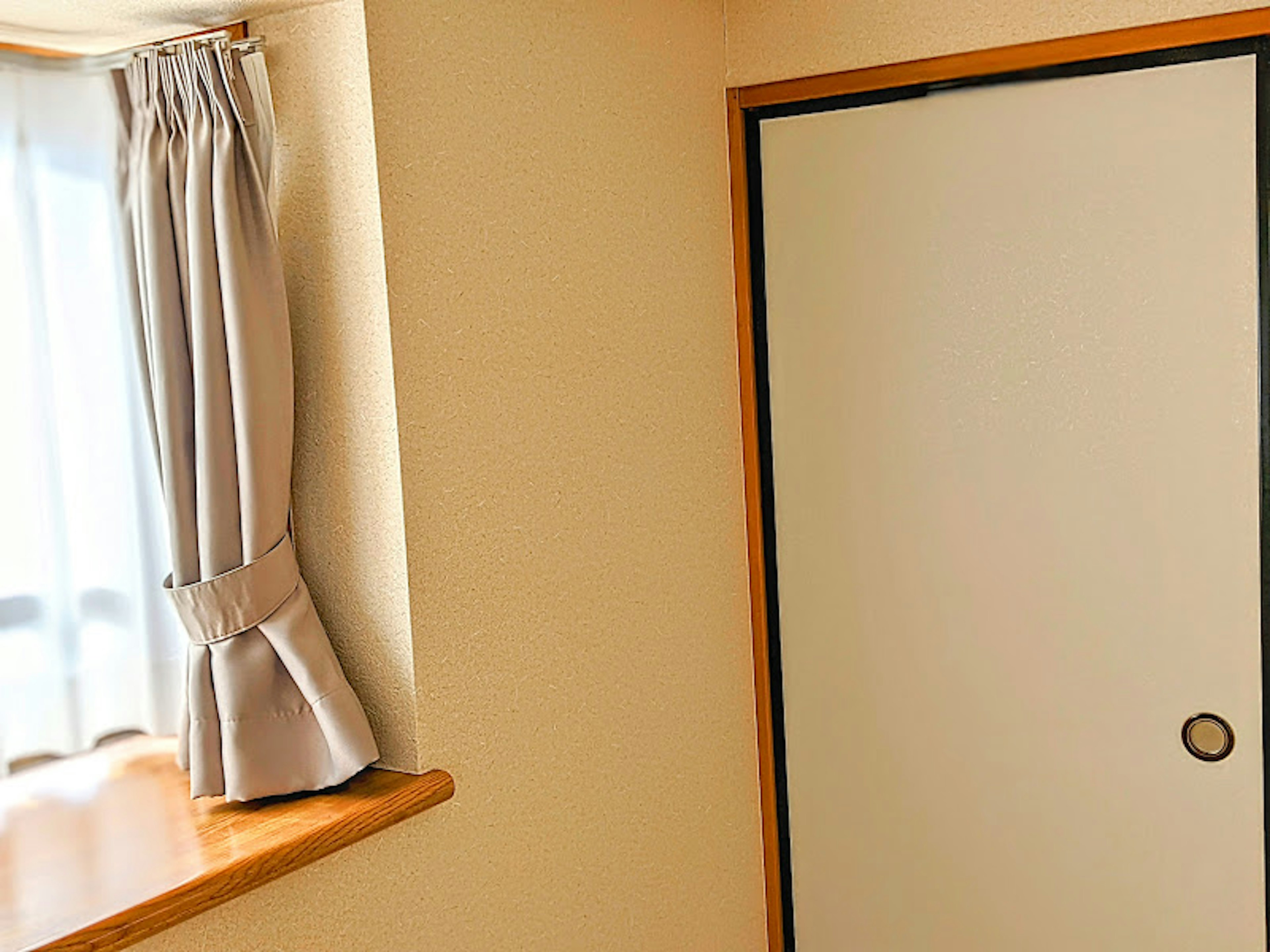 Esquina de una habitación con una puerta blanca y una ventana con cortinas