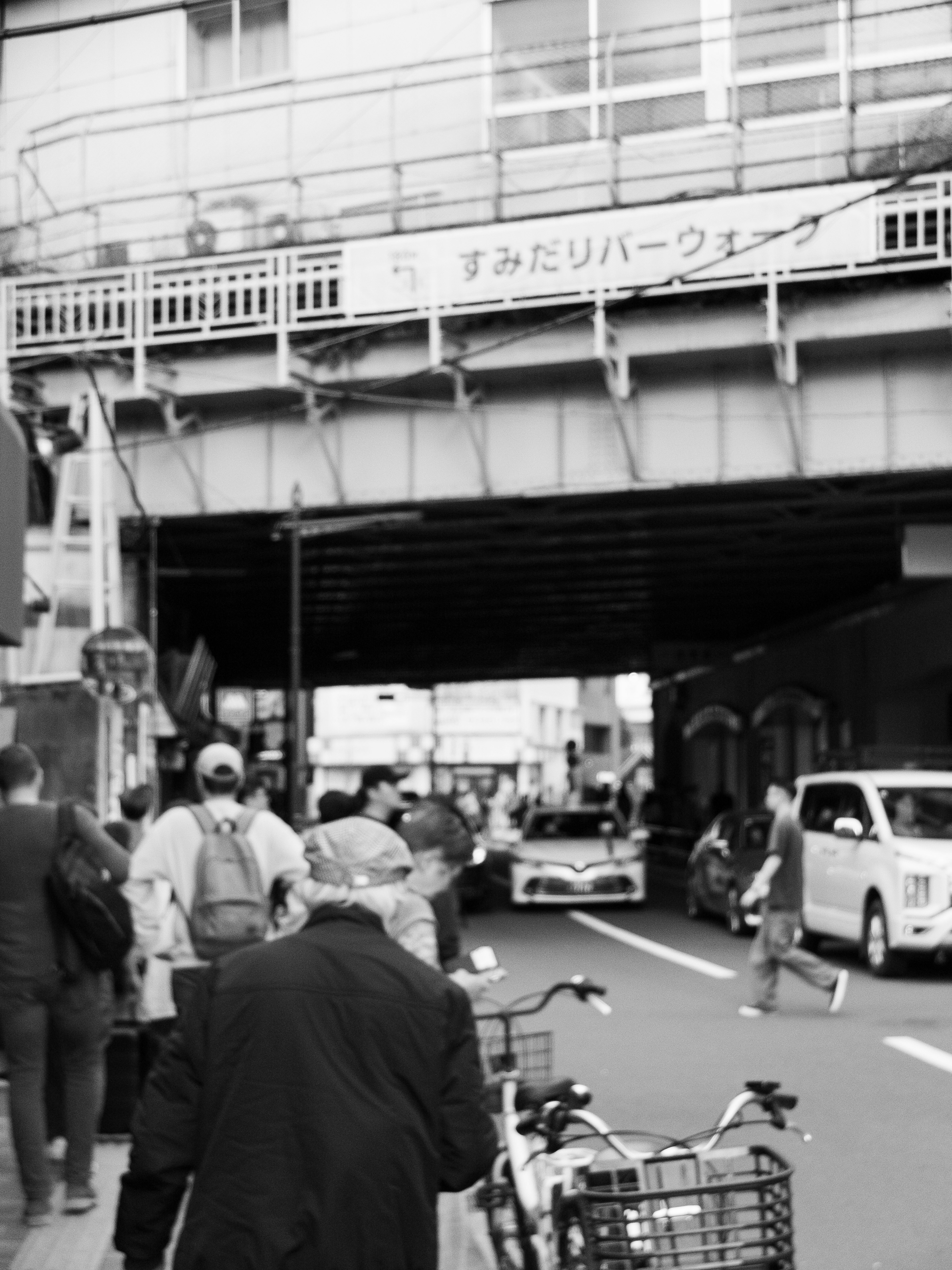 Une scène de rue animée sous un viaduc ferroviaire avec des piétons et des véhicules