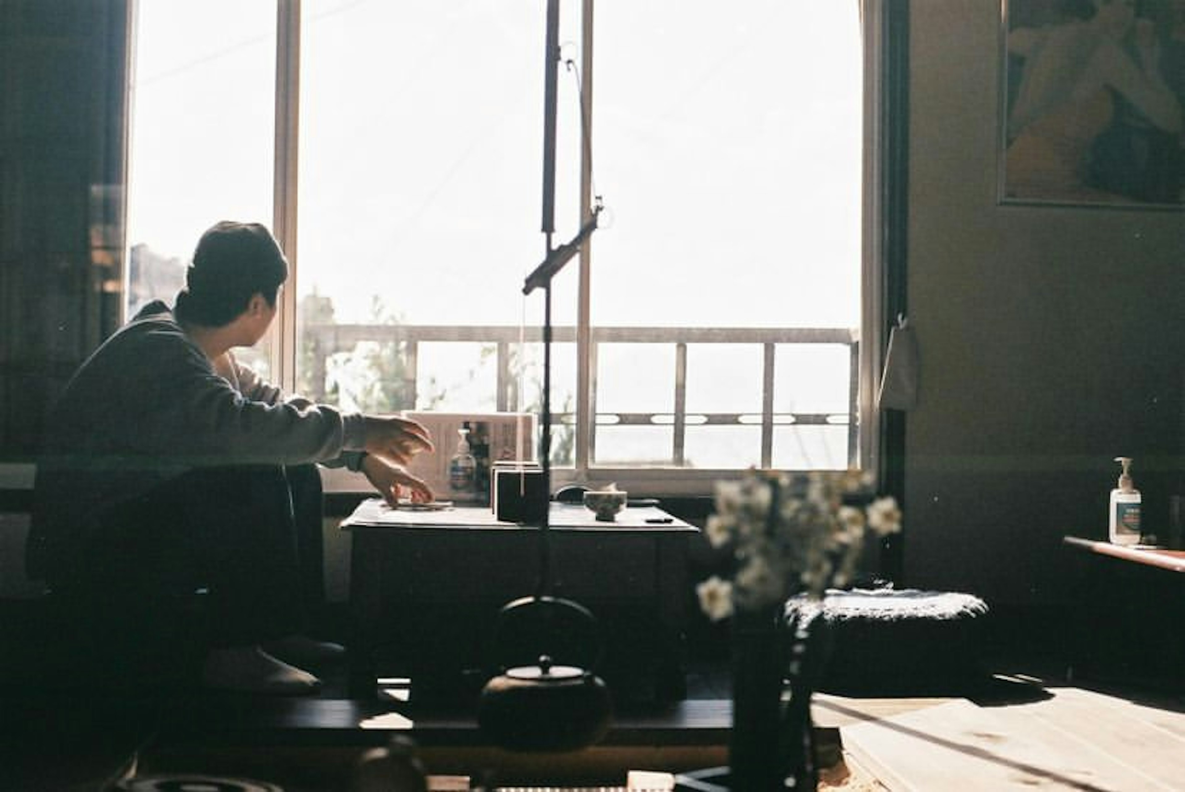 A young person sitting by the window deep in thought