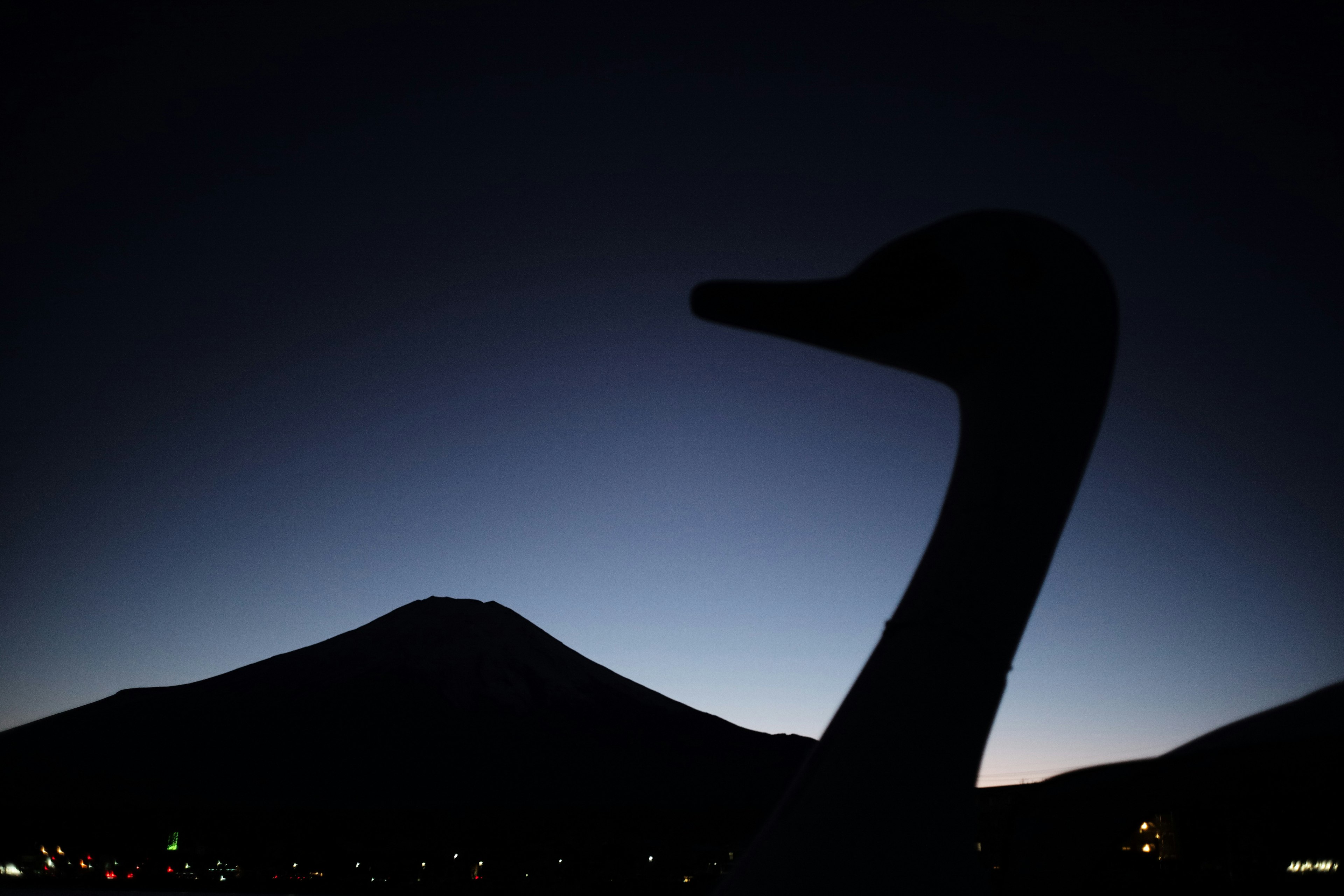 富士山のシルエットと夜空に浮かぶ白鳥の像