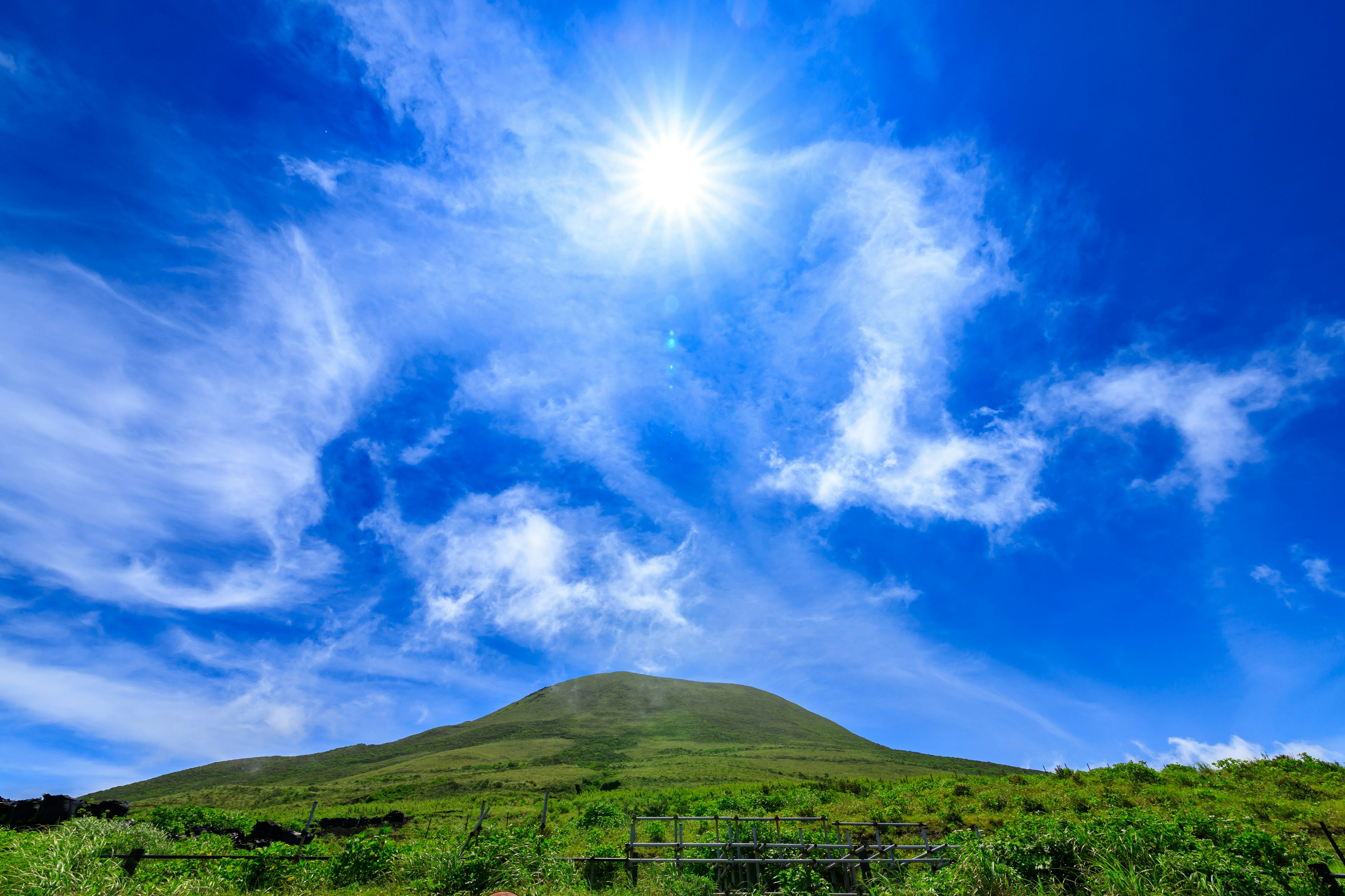 青い空と太陽の下に広がる緑の丘