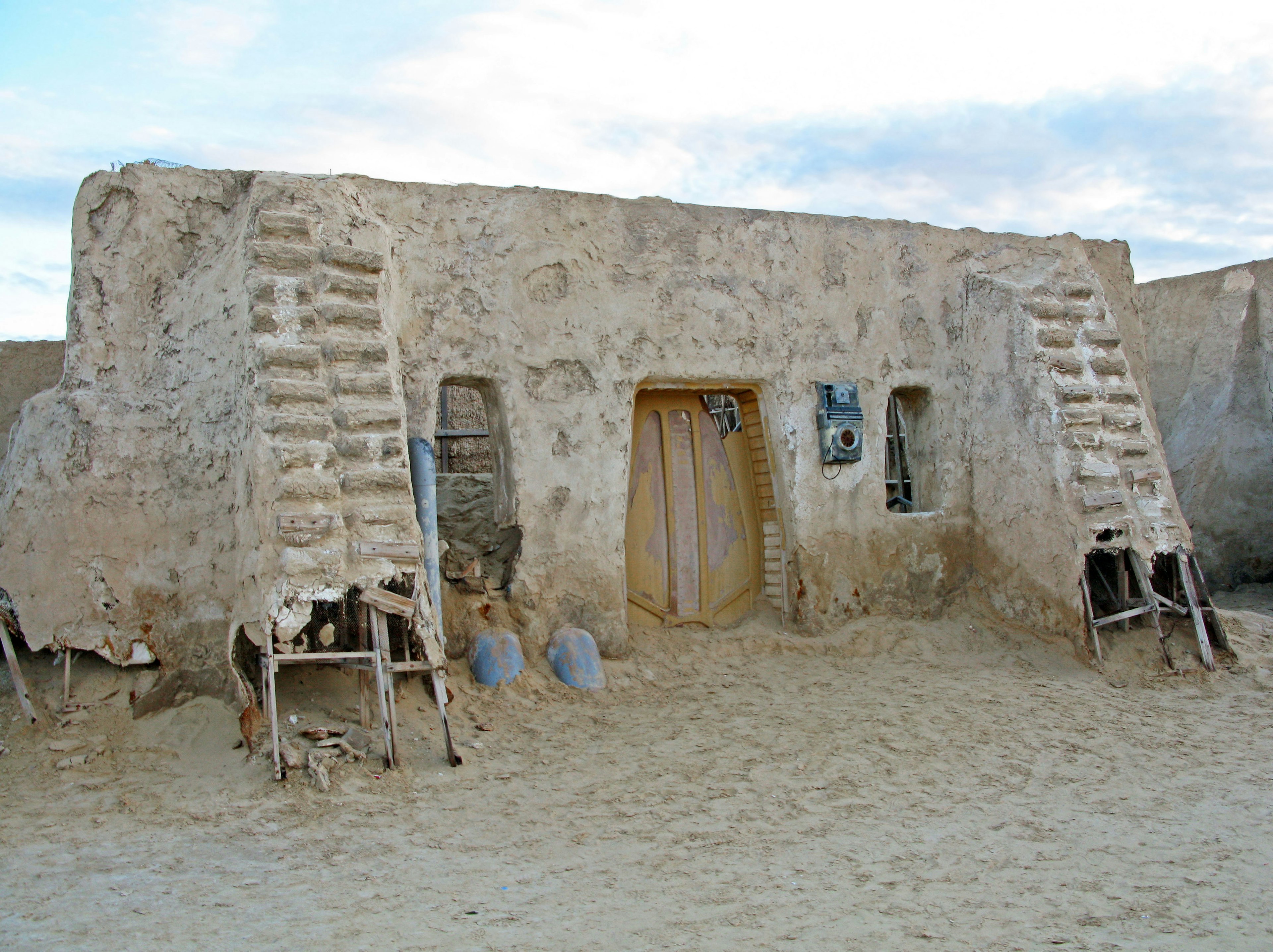 Rumah adobe tradisional di gurun dengan tangga kayu