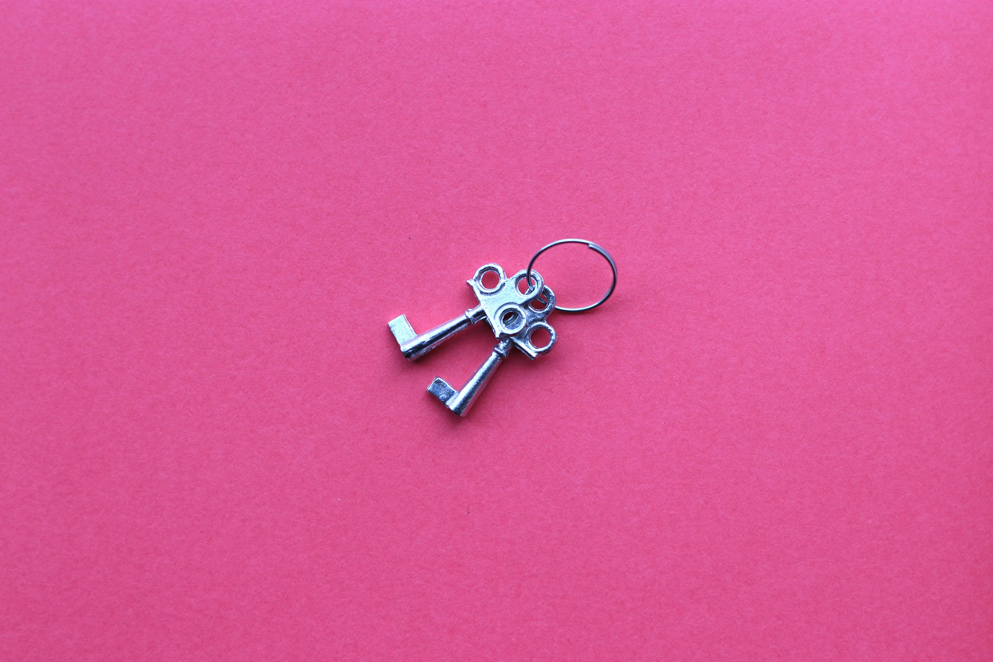 Metal key-shaped accessory placed on a pink background