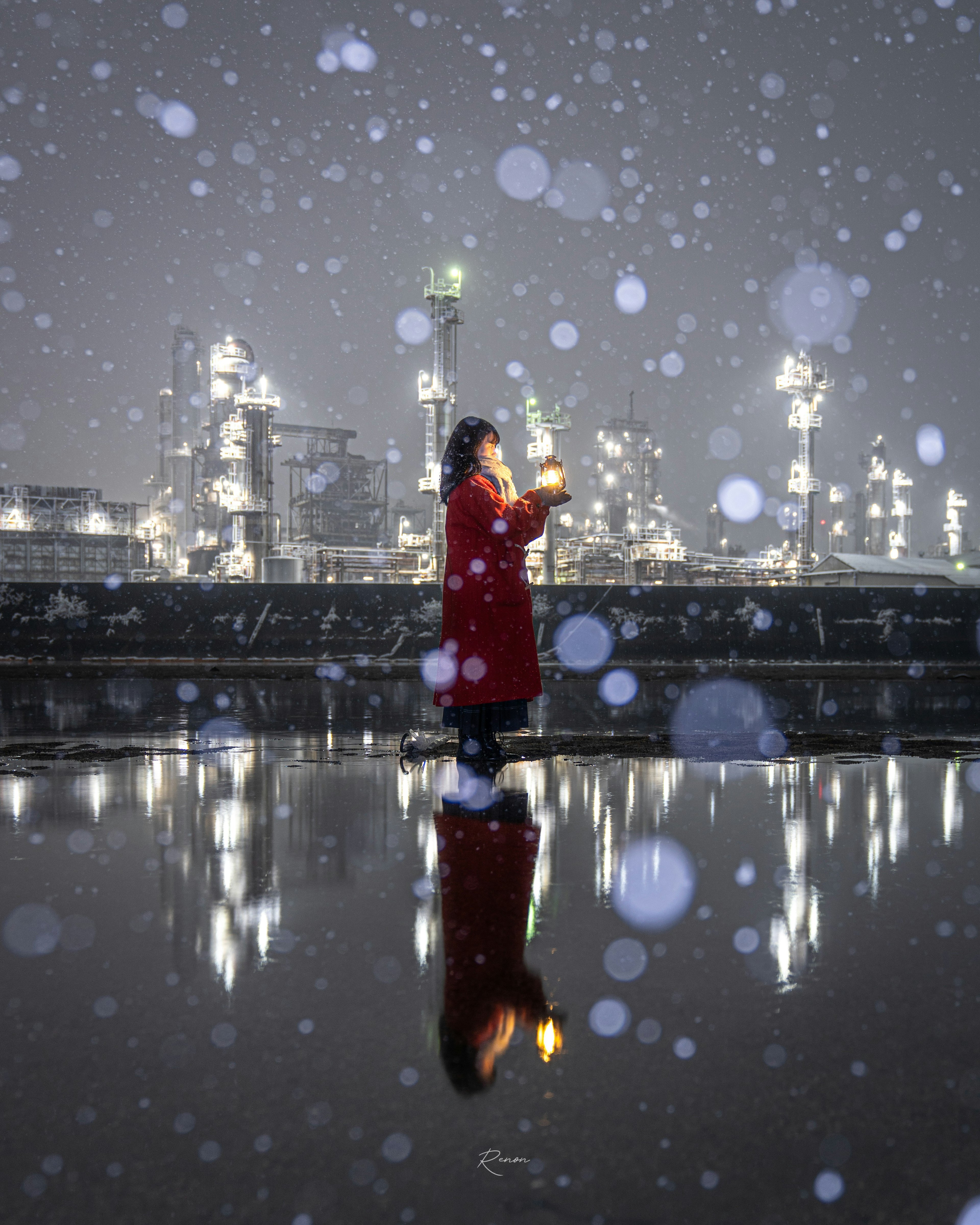 一个穿着红色外套的女人站在雪中，背景是反射面和工业灯光