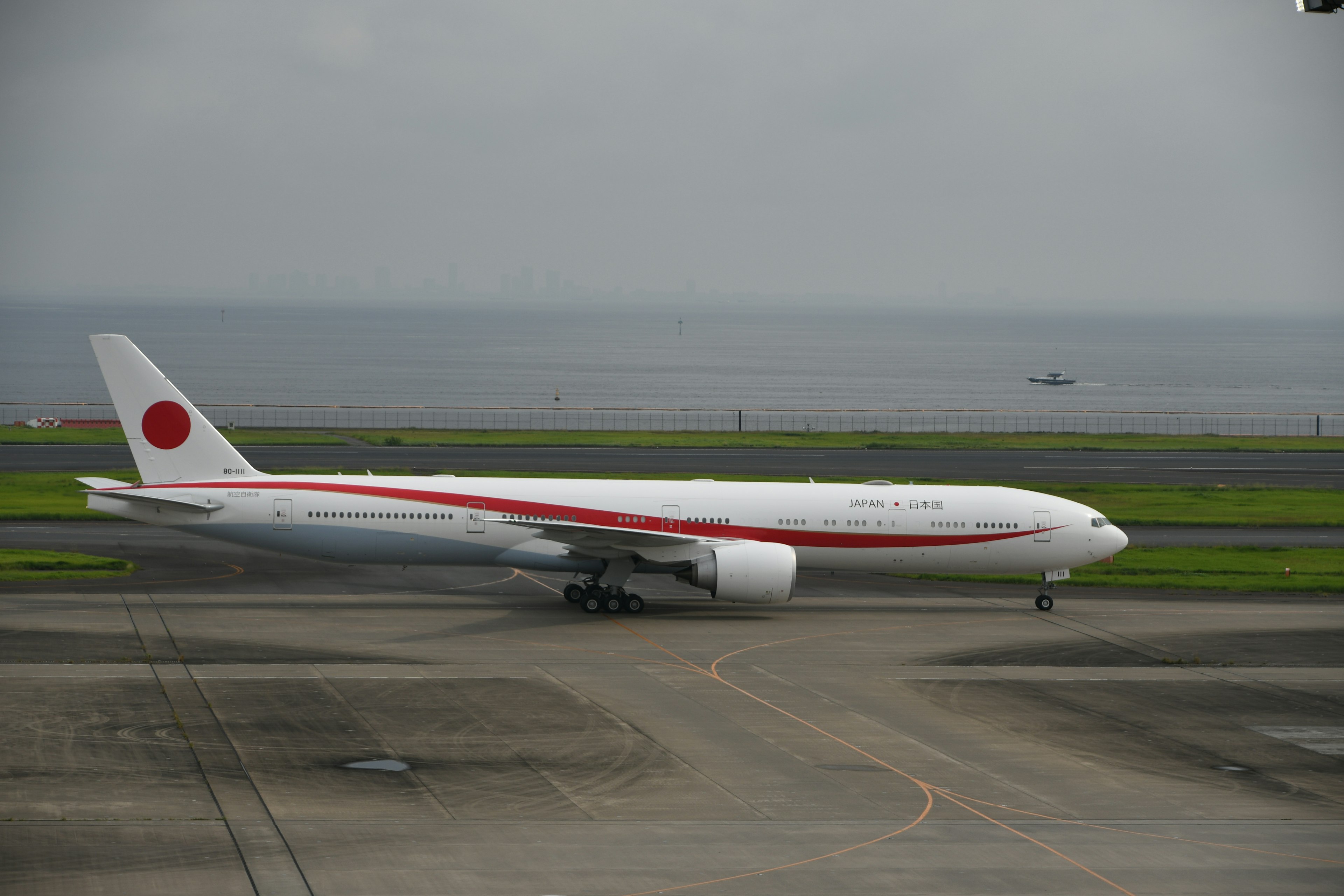 Japanese airplane taxiing on the runway featuring a red stripe