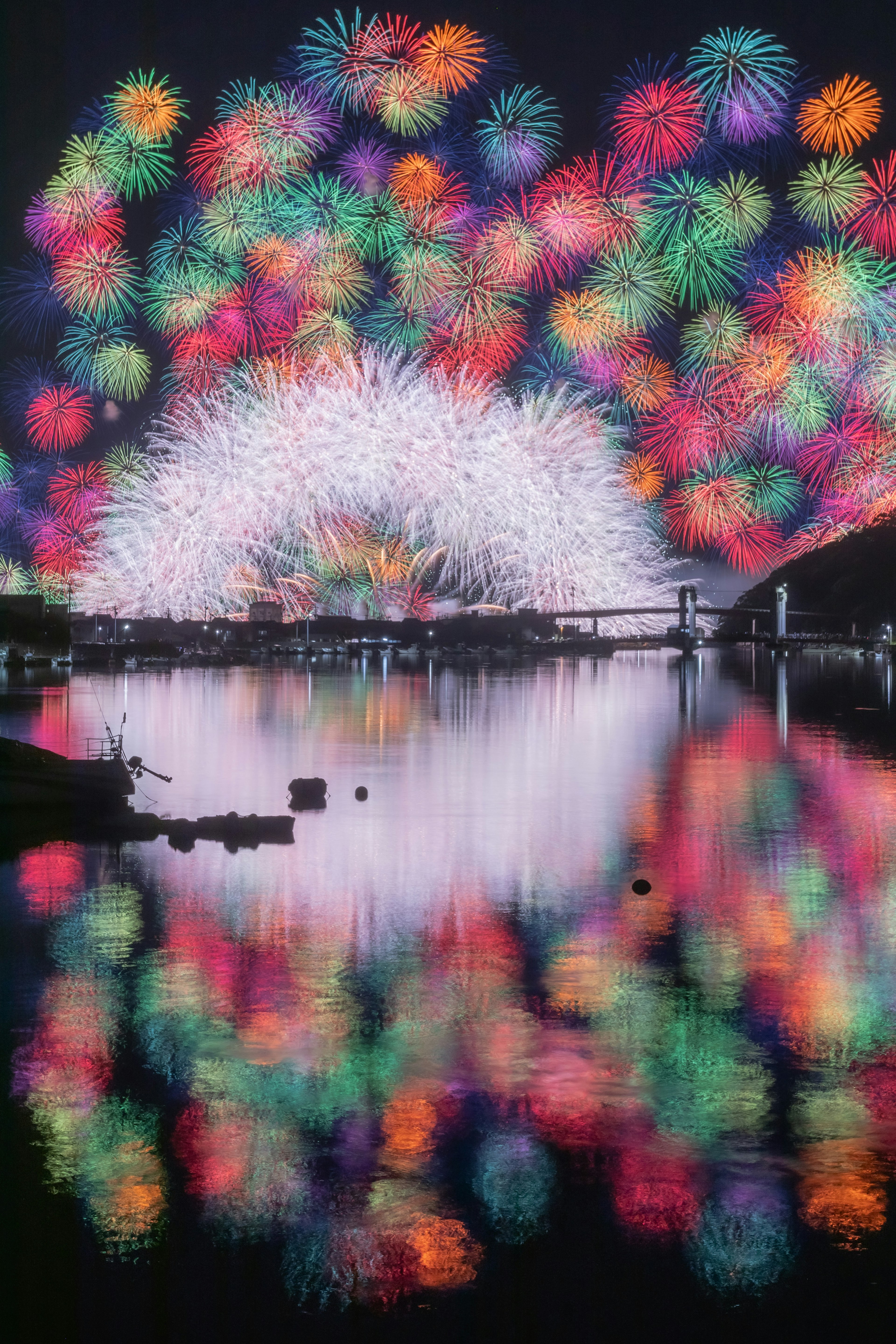 夜空に広がる色とりどりの花火とその反射が美しい湖の風景