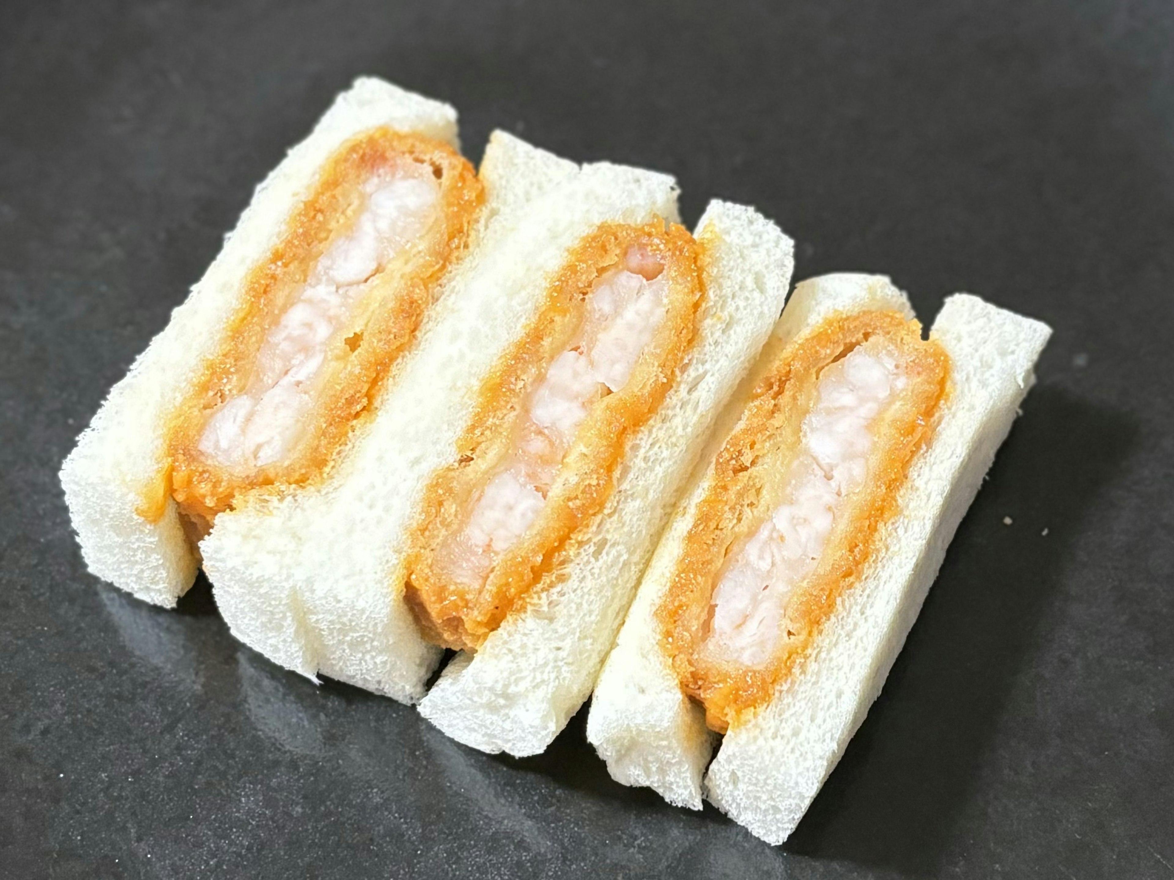 Foto tiga sandwich udang goreng di atas piring hitam